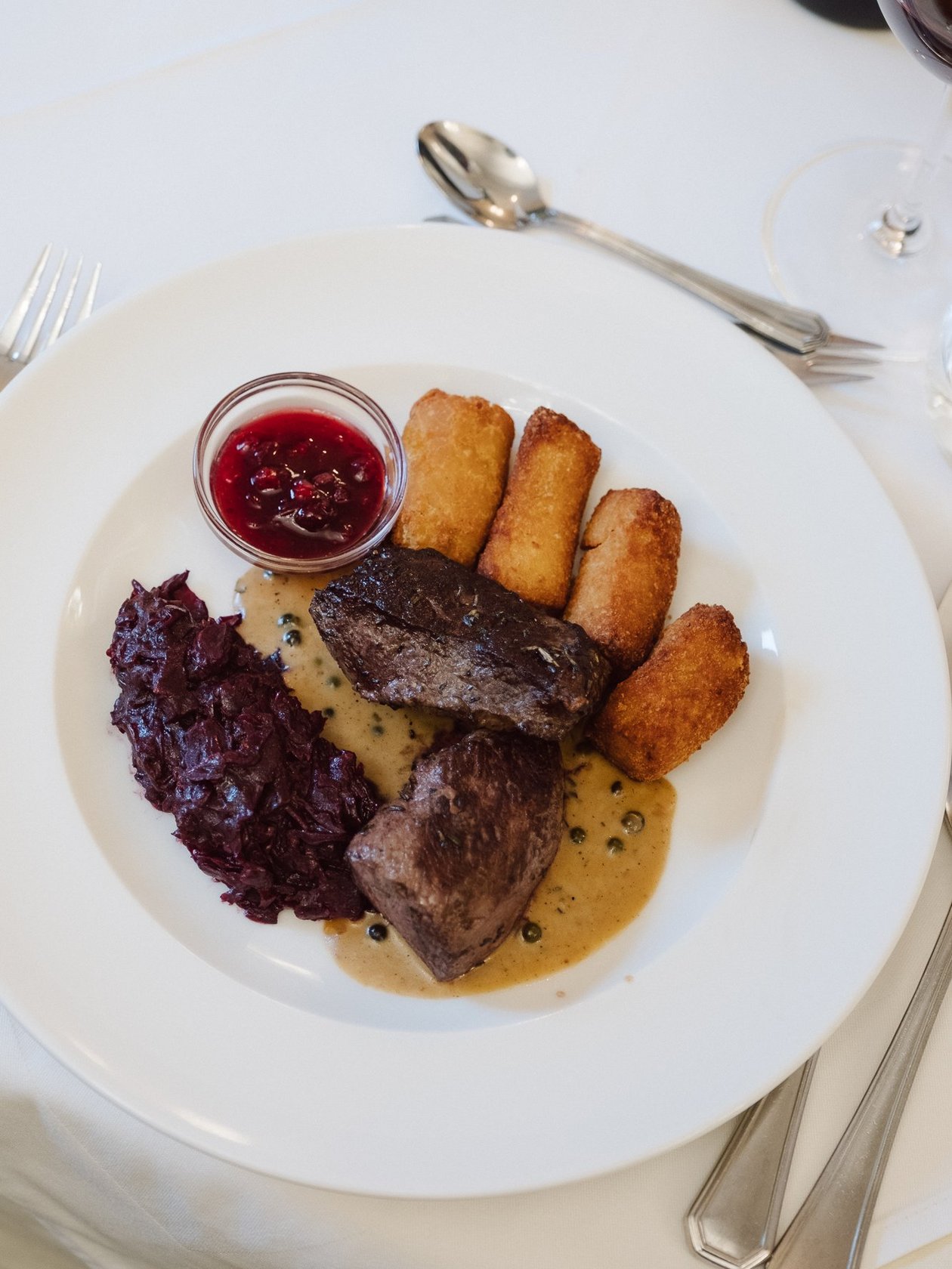 Gourmet Genuss mit Rindfleisch Gourmet Gericht mit Rindfleisch, Rotkohl, Kroketten und Sauce in eleganter Präsentation
