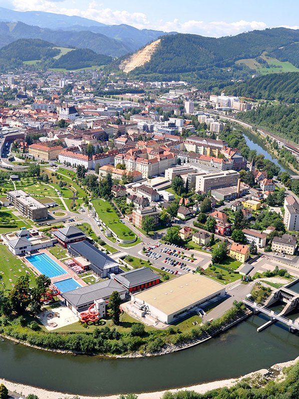 Luftaufnahme der Stadt Leoben Aerial view of Leoben cityscape with river and surrounding hills, showcasing urban development