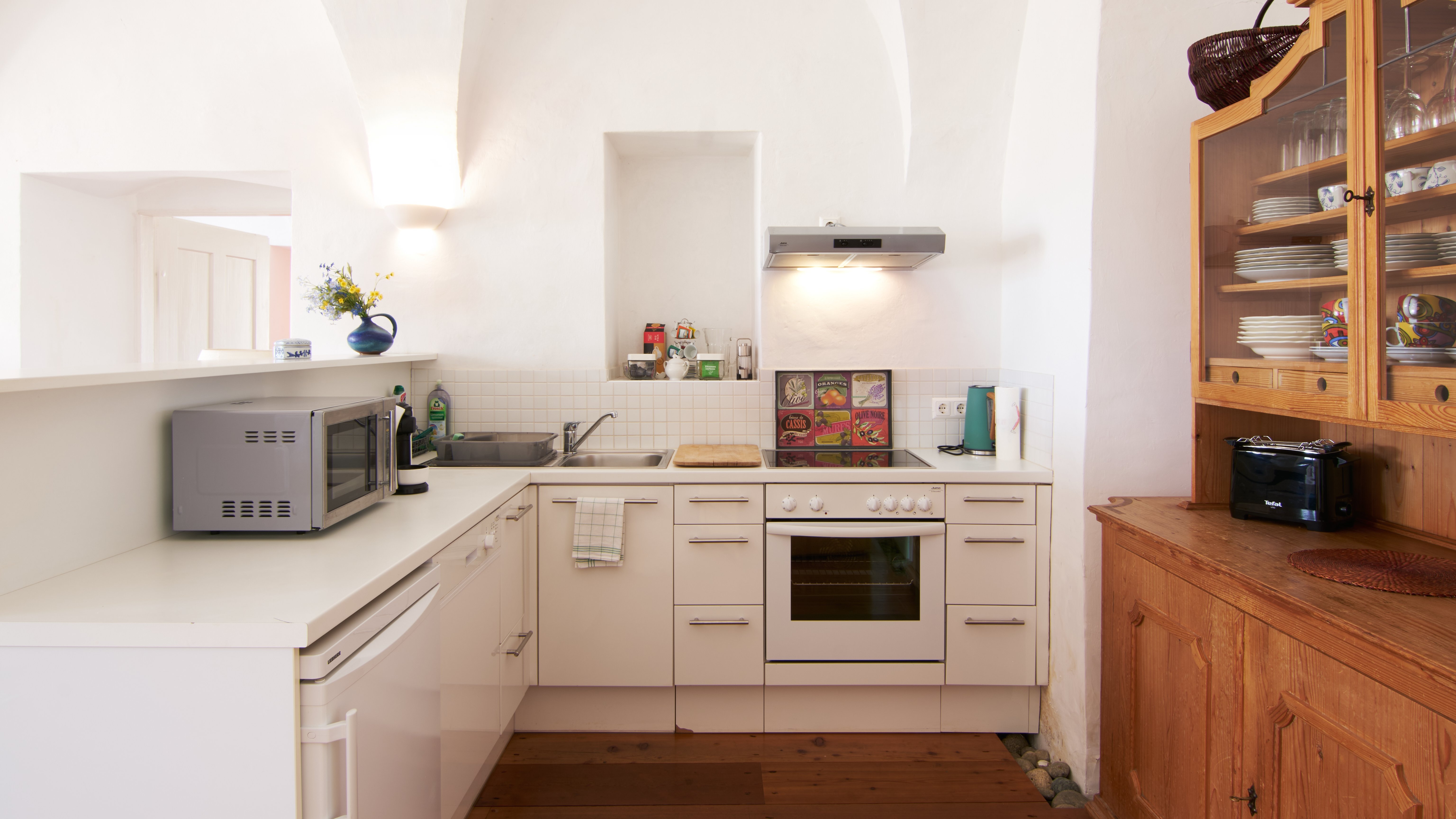 Contemporary Kitchen with Elegant Design A modern kitchen featuring white cabinetry, built-in oven and wooden sideboard under arched ceilings.