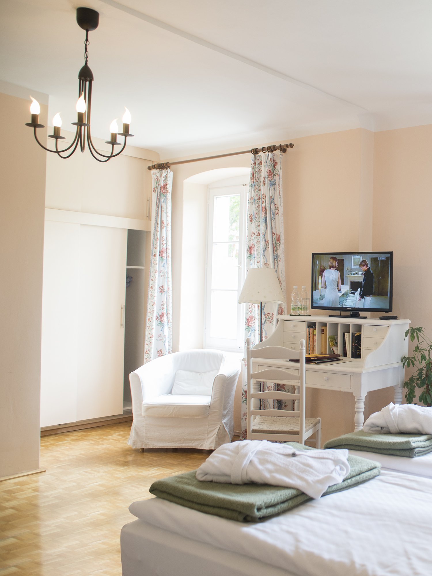 Gemütliches Hotelzimmer für entspannte Nächte Helles Hotelzimmer mit zwei Betten, Fernseher und Sitzbereich mit Stuhl und Tisch
