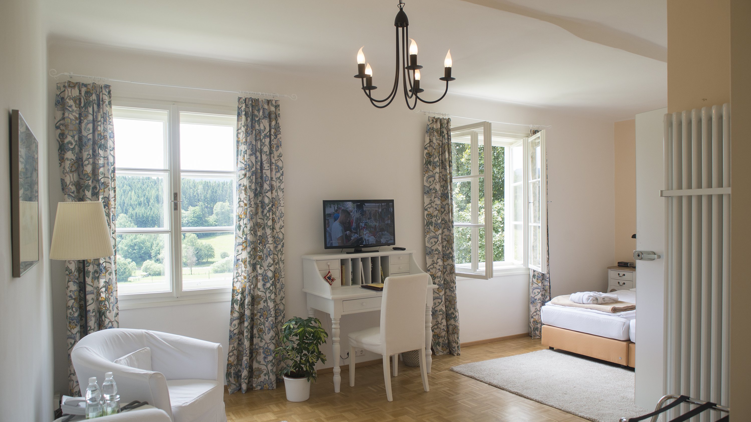 Bright and inviting interior space Spacious room with natural light, featuring a living area with a chair and desk, and a bedroom with a bed.