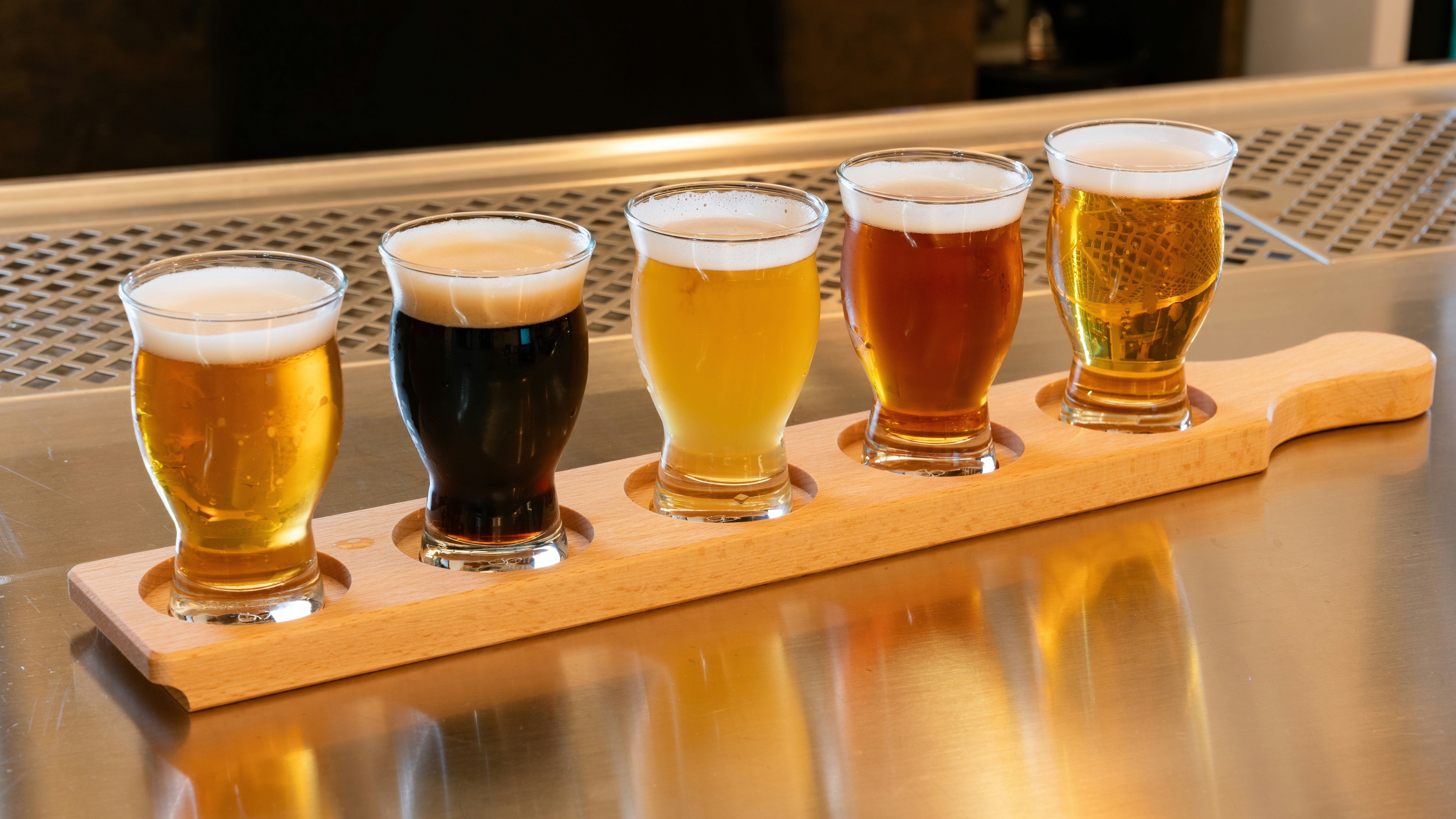 Vielfalt an Craft-Bieren Ein Holztablett mit fünf verschiedenen Biergläsern in unterschiedlichen Stilen und Farben.