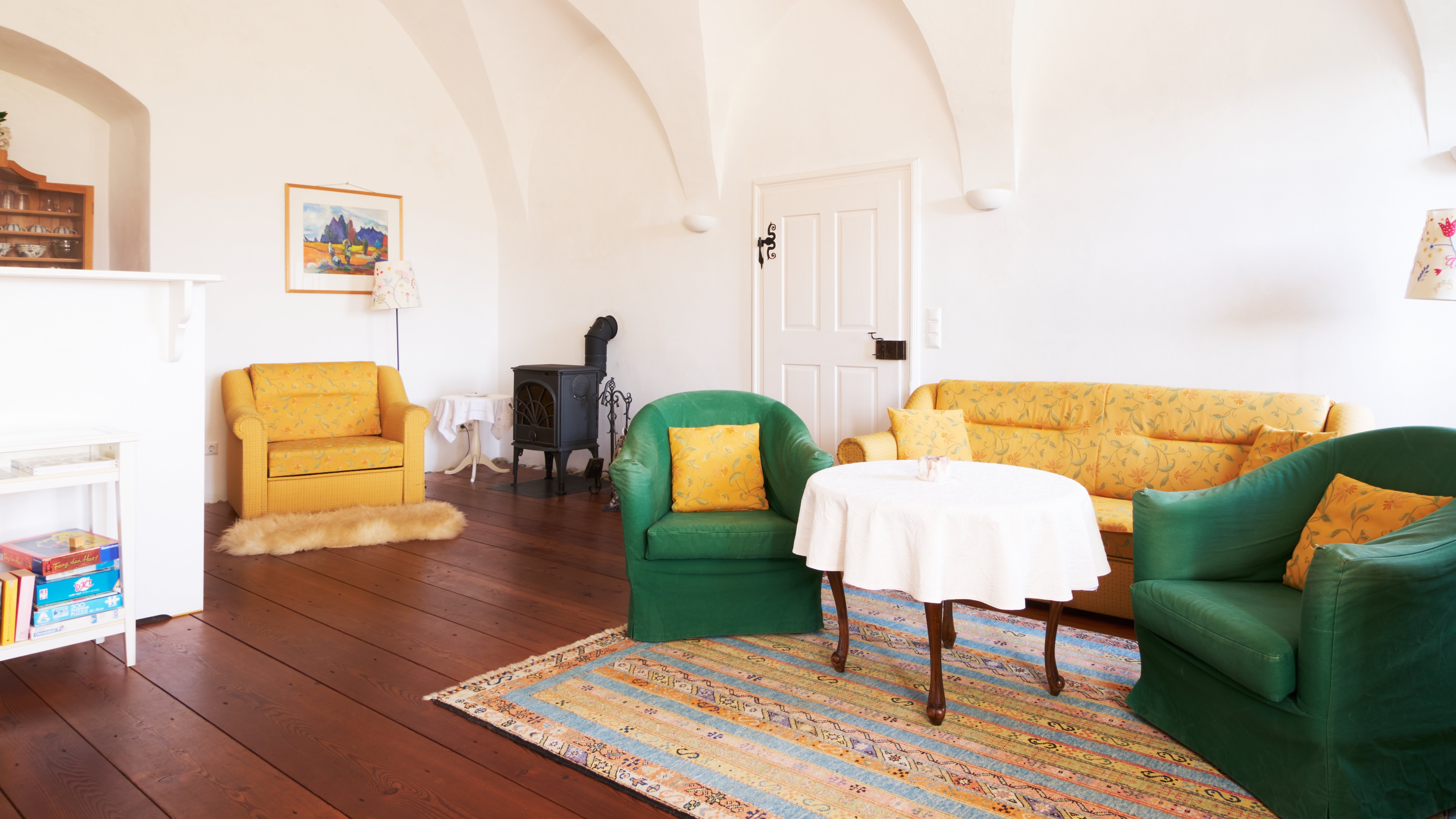 Gemütlicher Wohnraum im Pichlschloss Heller Wohnraum mit gewölbten Decken, grüner und gelber Einrichtung sowie einem kleinen Tisch