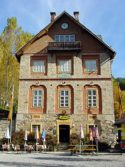 Historisches Gebäude im Grünen Historisches Bauwerk mit Steinfassade, großen Fenstern und Balkon in der Natur mit Bäumen und Außenplätzen.