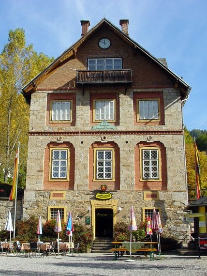 Historisches Gebäude im Grünen Historisches Bauwerk mit Steinfassade, großen Fenstern und Balkon in der Natur mit Bäumen und Außenplätzen.