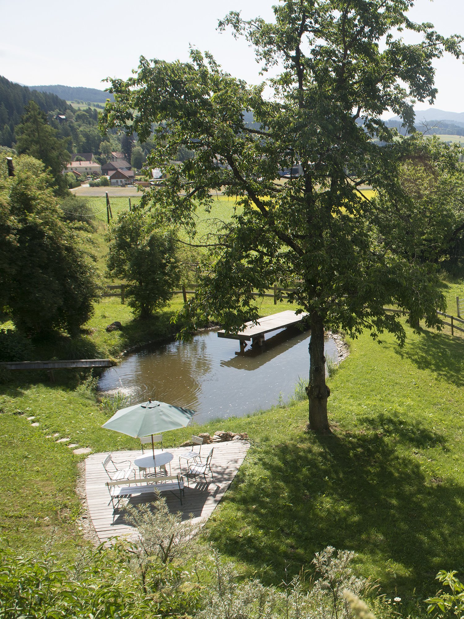 Landschaft mit Teich, Bäumen und sanften Hügeln im Hintergrund in einer idyllischen Umgebung