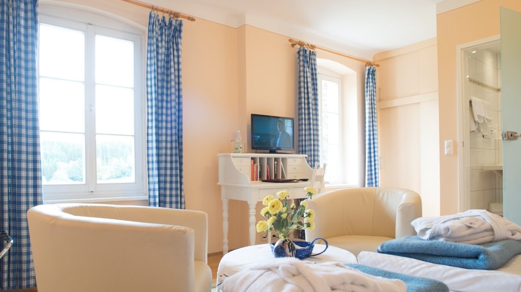 Cozy hotel room with modern amenities Bright hotel room featuring a cozy seating area and white chairs around a small table with flowers