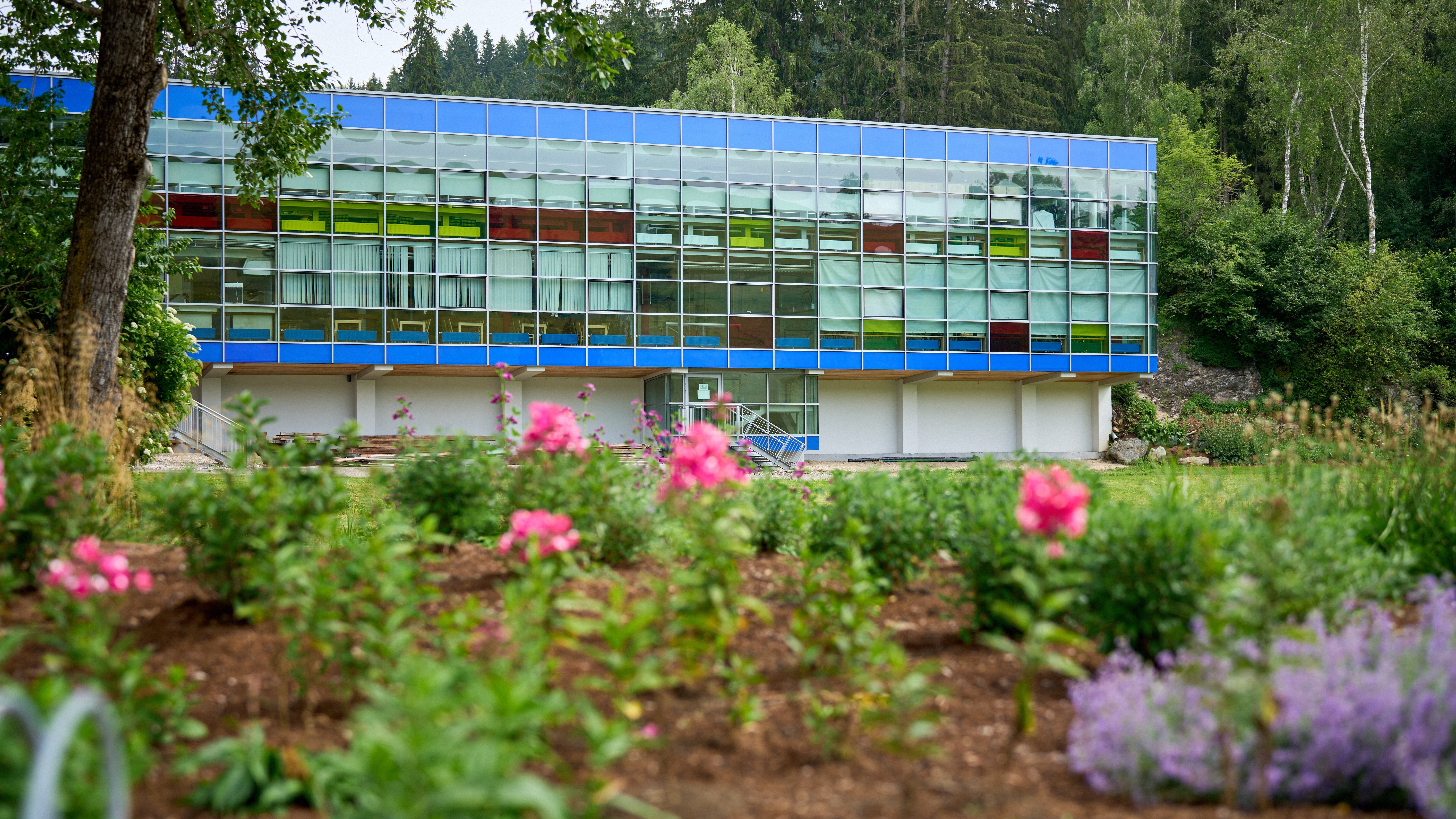 Modernes Gebäude mit bunten Fenstern und Gartenlandschaft umgeben von Grünflächen