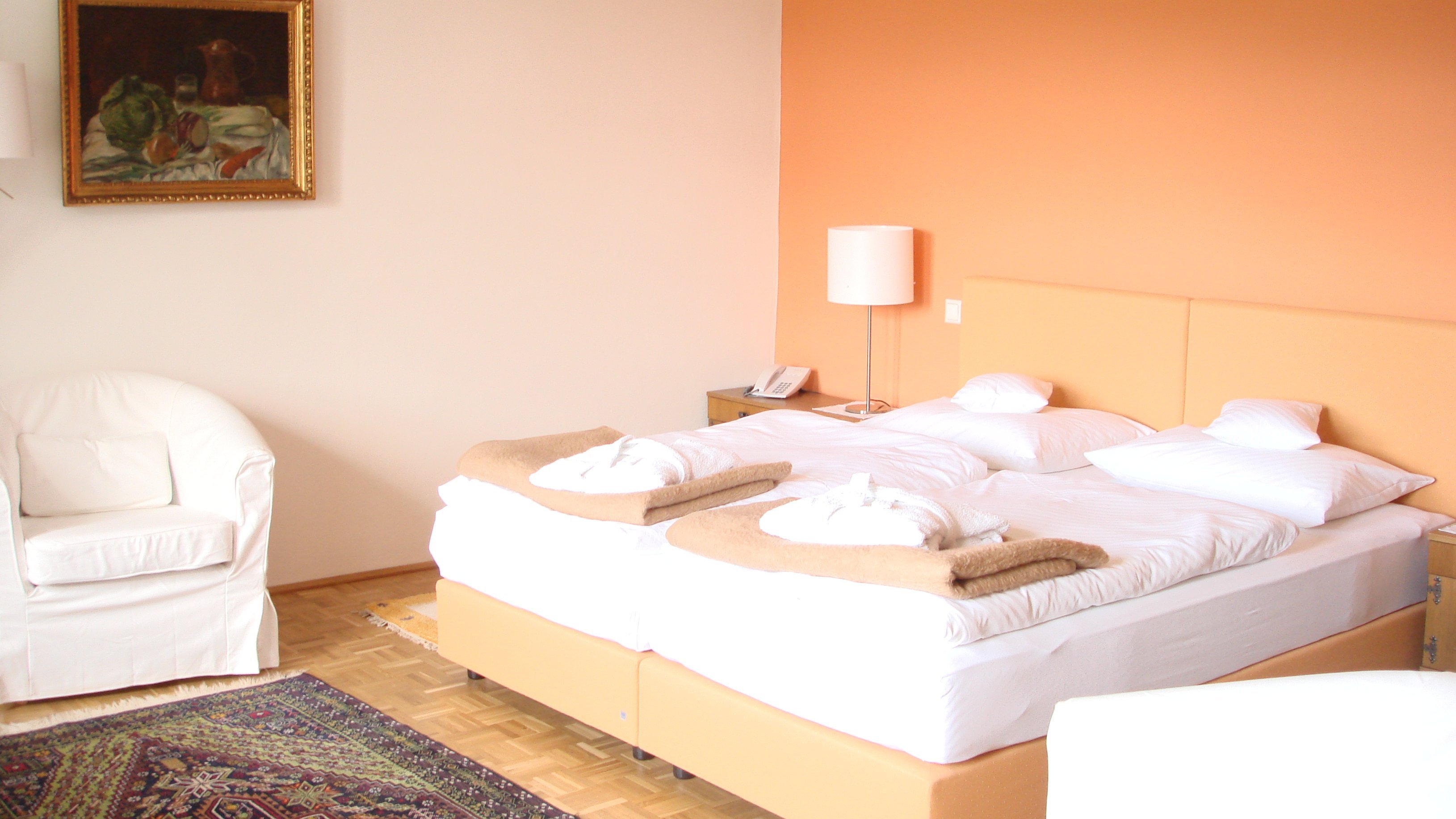 Einladendes Zimmer für erholsame Nächte Helle Hotelzimmer mit Doppelbett, gemalter Wandkunst und gemütlicher Sitzecke im Innenbereich