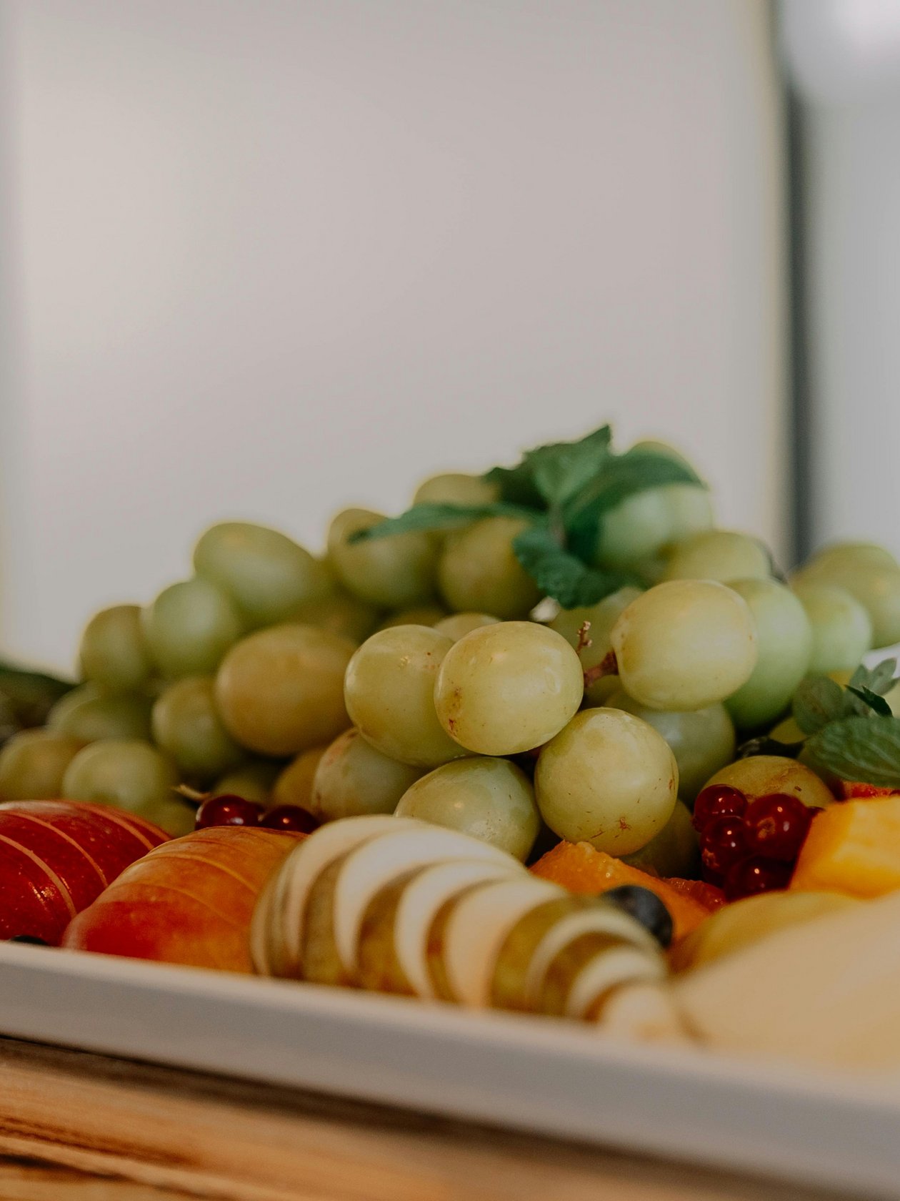 Frische Obstplatte für gesunde Snacks Bunte Obstplatte mit Trauben, Äpfeln und verschiedenen frischen Früchten auf einem Teller