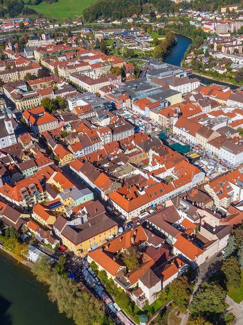 Aerial view of a town featuring a mix of residential and commercial buildings with red roofs and green spaces