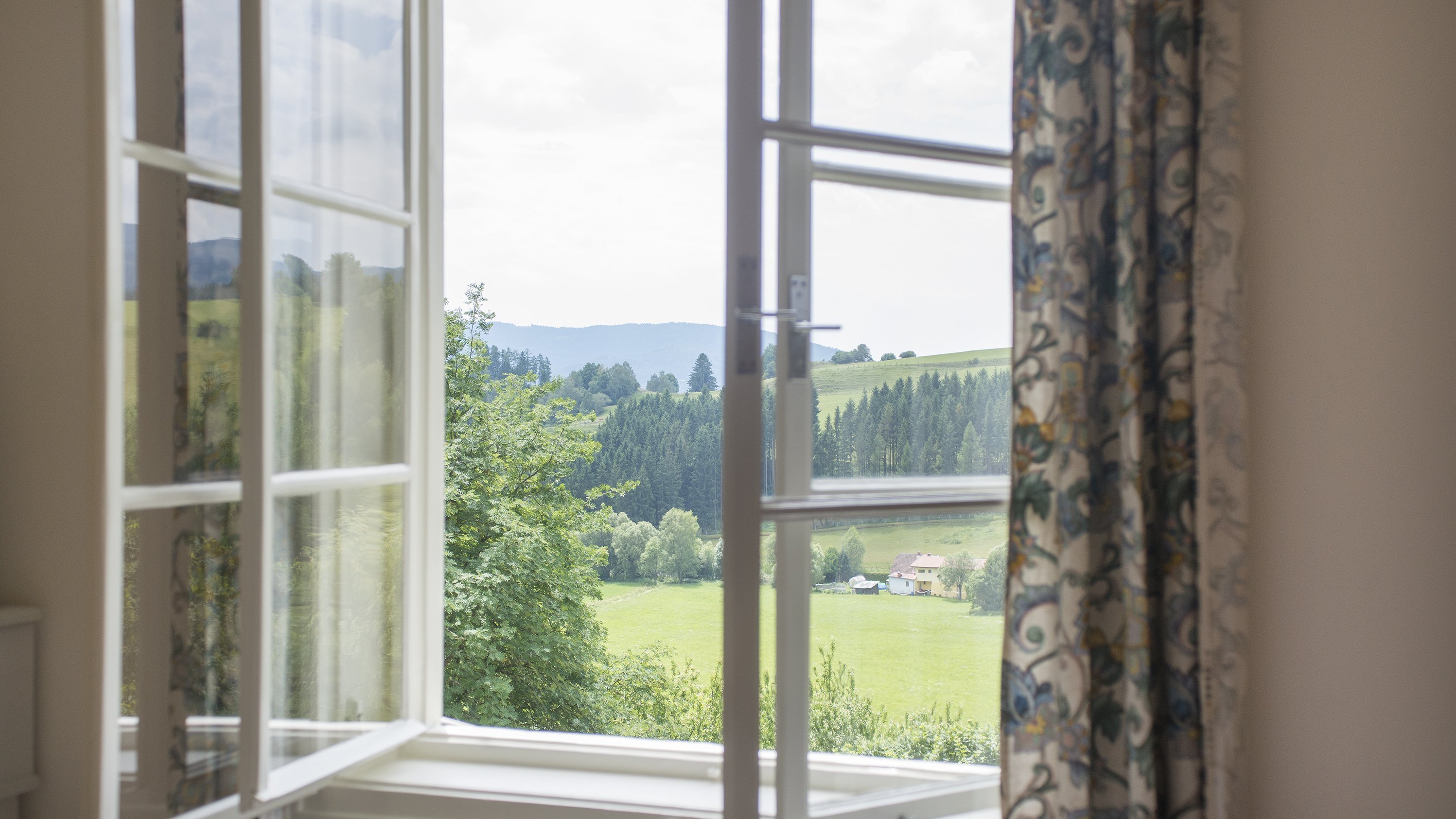 Ausblick auf die grüne Landschaft Offenes Fenster mit Blick auf eine grüne Hügellandschaft und Bäume im Hintergrund