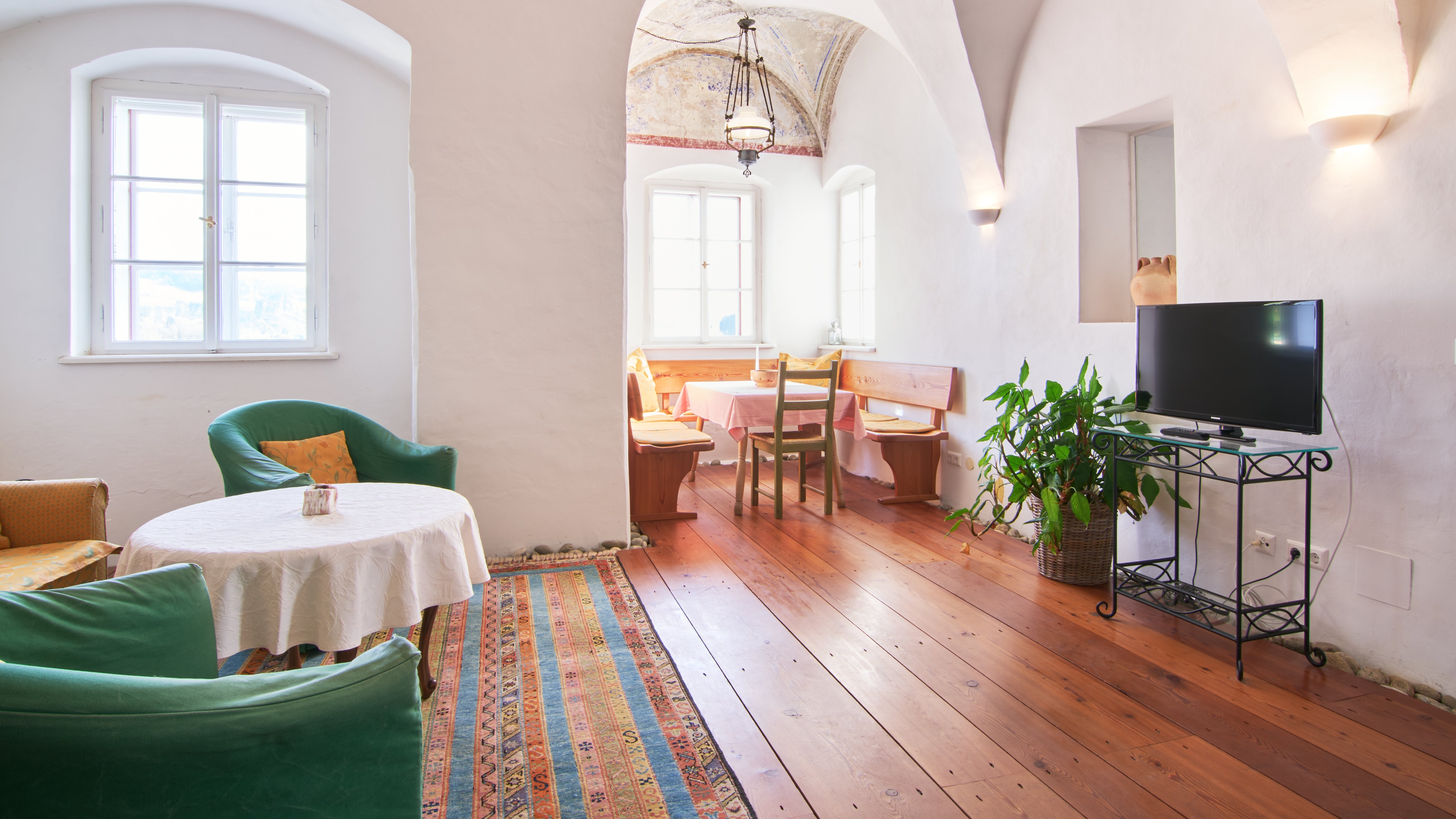 Einladendes Wohnzimmer im Pischlschloss Gemütliches Wohnzimmer mit hohen gewölbten Decken, grünen Stühlen und einem Tisch