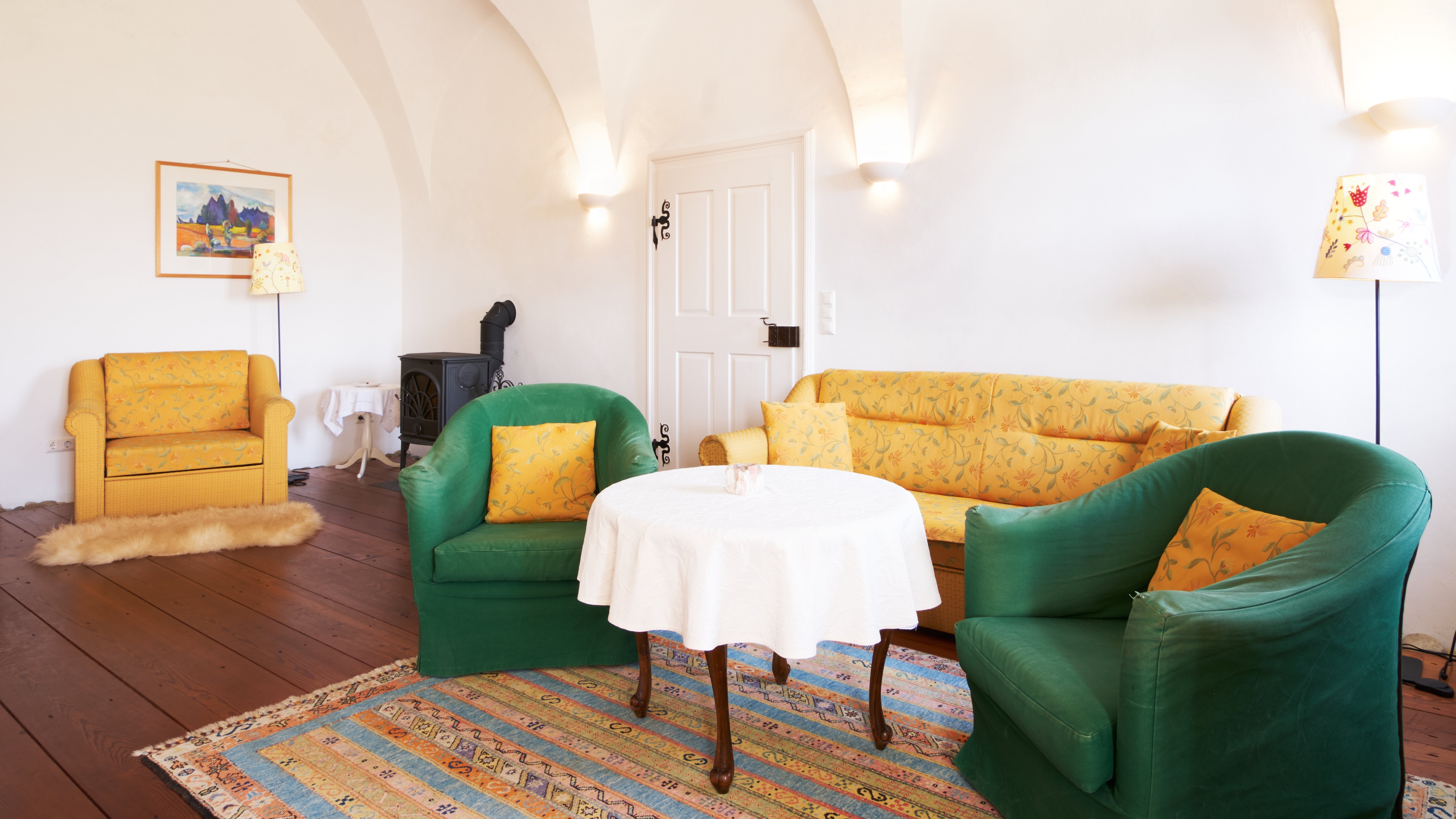 Gemütliches Wohnzimmer mit stilvollen Möbeln Ein einladendes Wohnzimmer mit gelbem Sofa, grünen Sesseln und einem runden Tisch