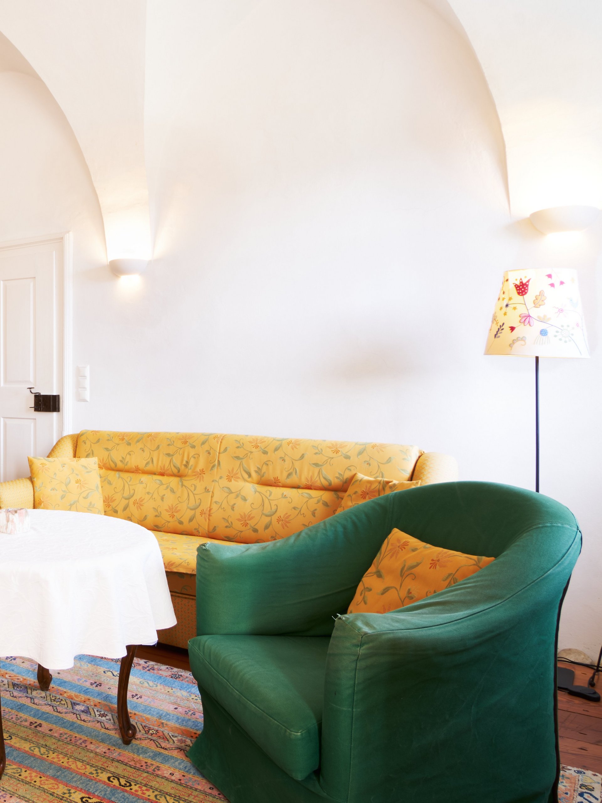 Ein einladendes Wohnzimmer mit gelbem Sofa, grünen Sesseln und einem runden Tisch