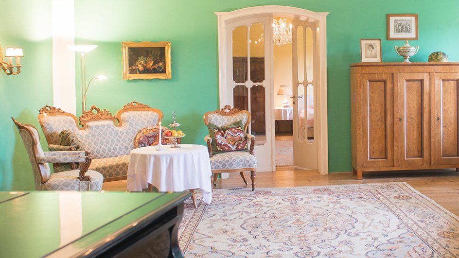 Ein Wohnzimmer mit grünen Wänden, vintage Möbeln und dekorativen Elementen. Ideal für stilvolle Inneneinrichtungen.
