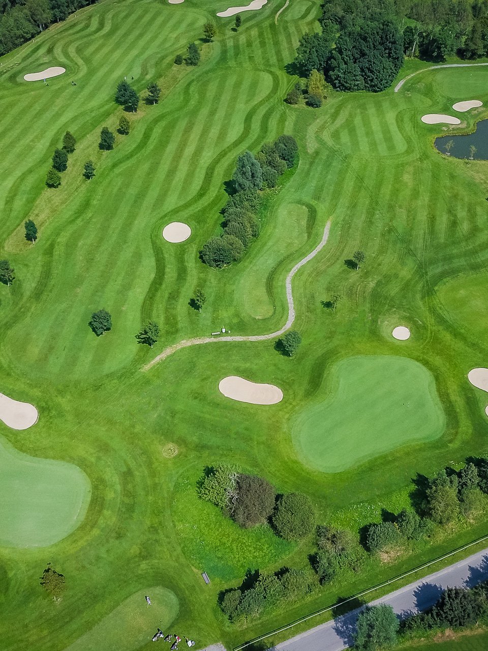 Atemberaubende Sicht auf den Golfplatz Luftaufnahme eines Golfplatzes mit Greens, Bunkern und einem Teich inmitten von Bäumen