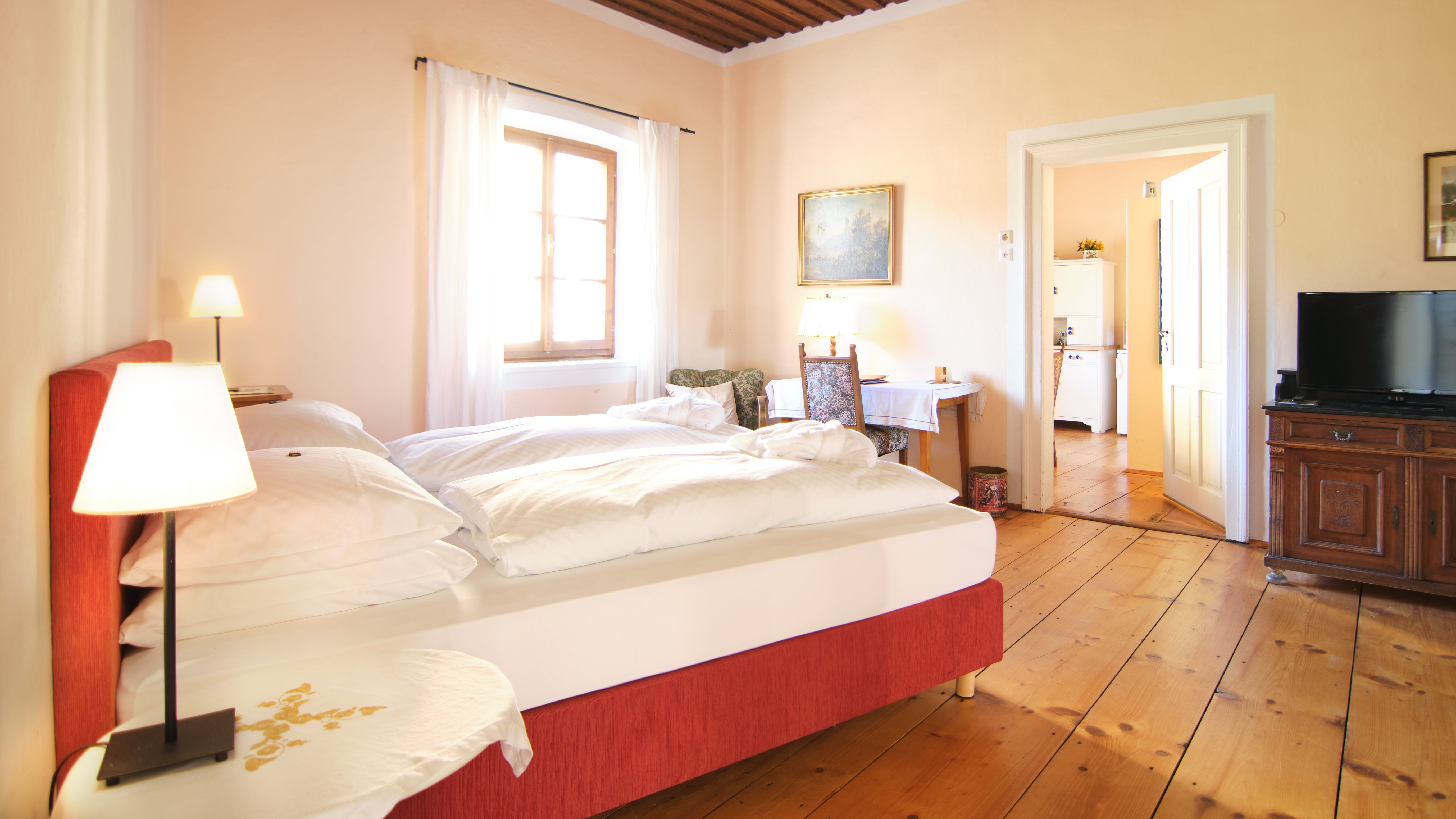 Helle Atmosphäre im Schlafzimmer Geräumiges Schlafzimmer mit einem Doppelbett und Holzfußboden, Fenster bringt Tageslicht.