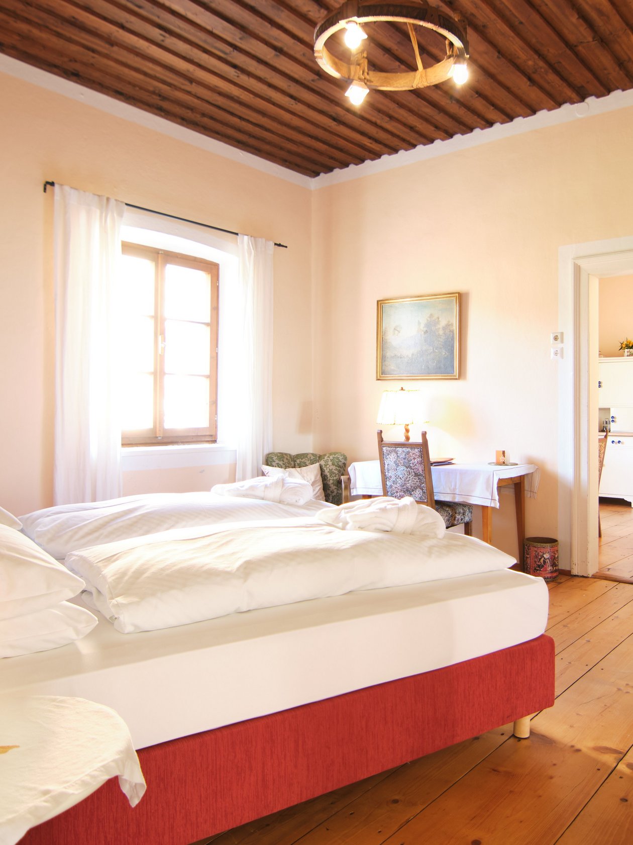 Helle Atmosphäre im Schlafzimmer Geräumiges Schlafzimmer mit einem Doppelbett und Holzfußboden, Fenster bringt Tageslicht.