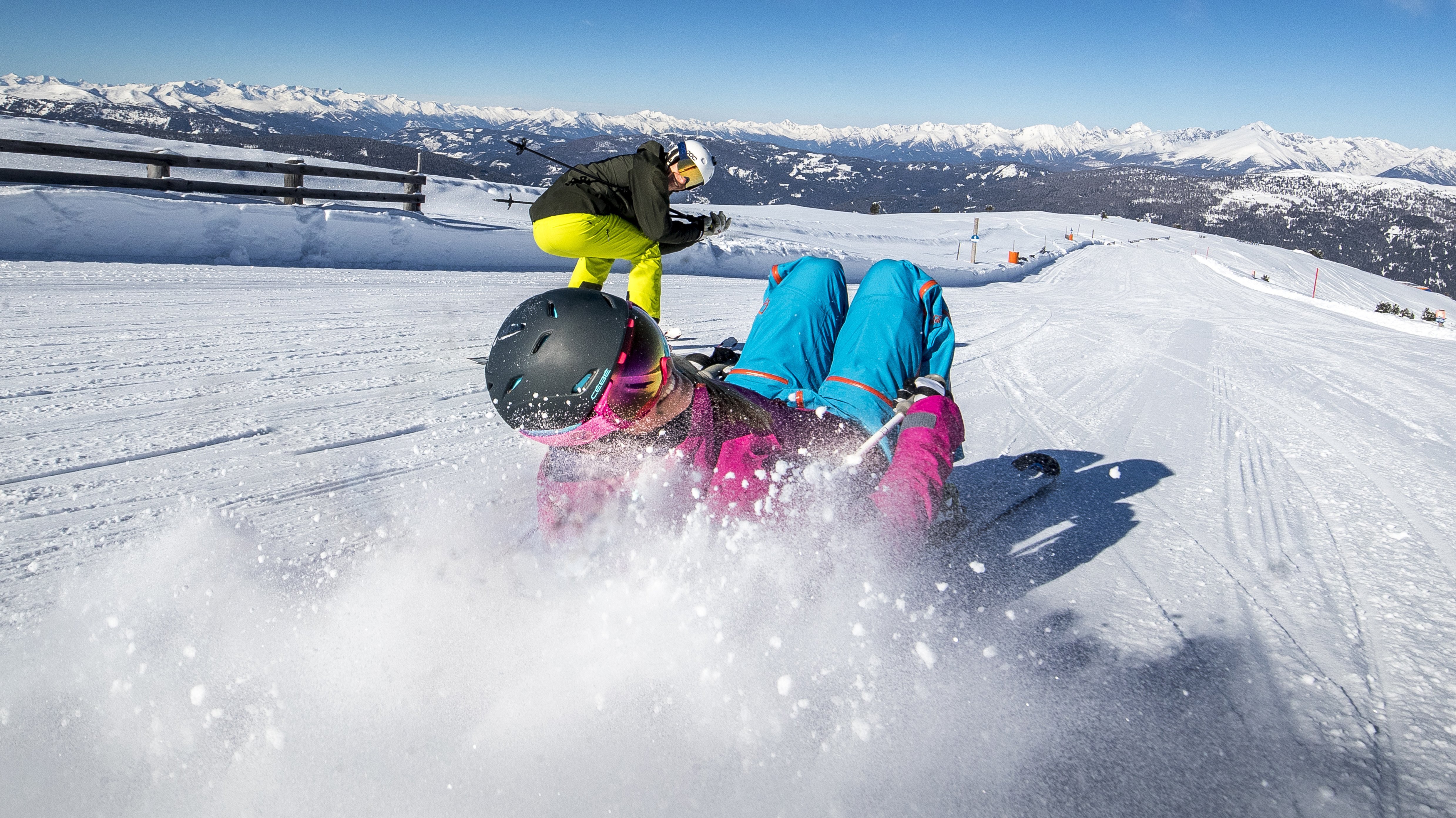 Wintervergnügen auf den Pisten Zwei Personen beim Skifahren auf einer schneebedeckten Piste mit Bergen im Hintergrund