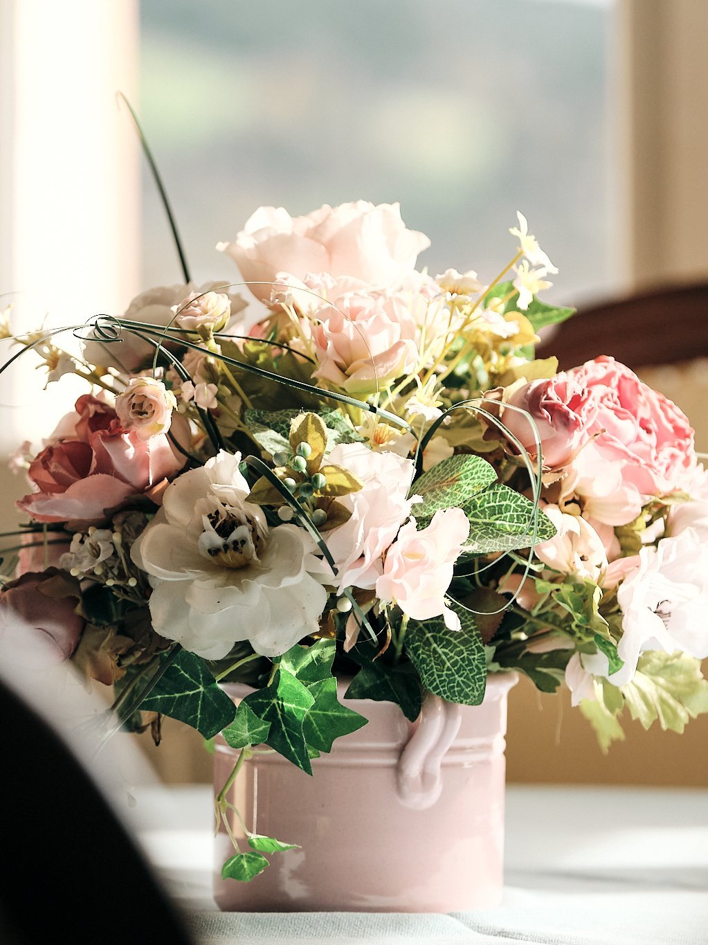 Dekorativer Blumenstrauß in einer Vase mit verschiedenen Blumen und Grünpflanzen.