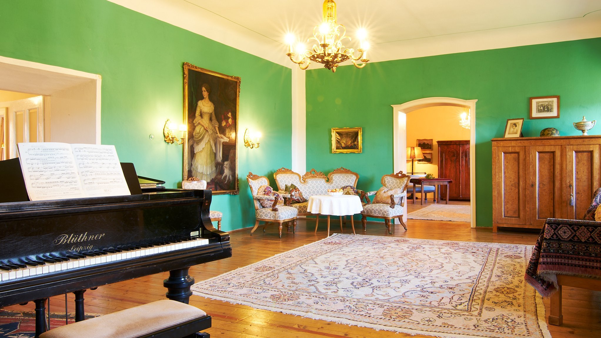 Eleganter Salon mit Klavier Wohnzimmer mit großem Klavier, vintage Möbeln und grünen Wänden in einem stilvollen Ambiente