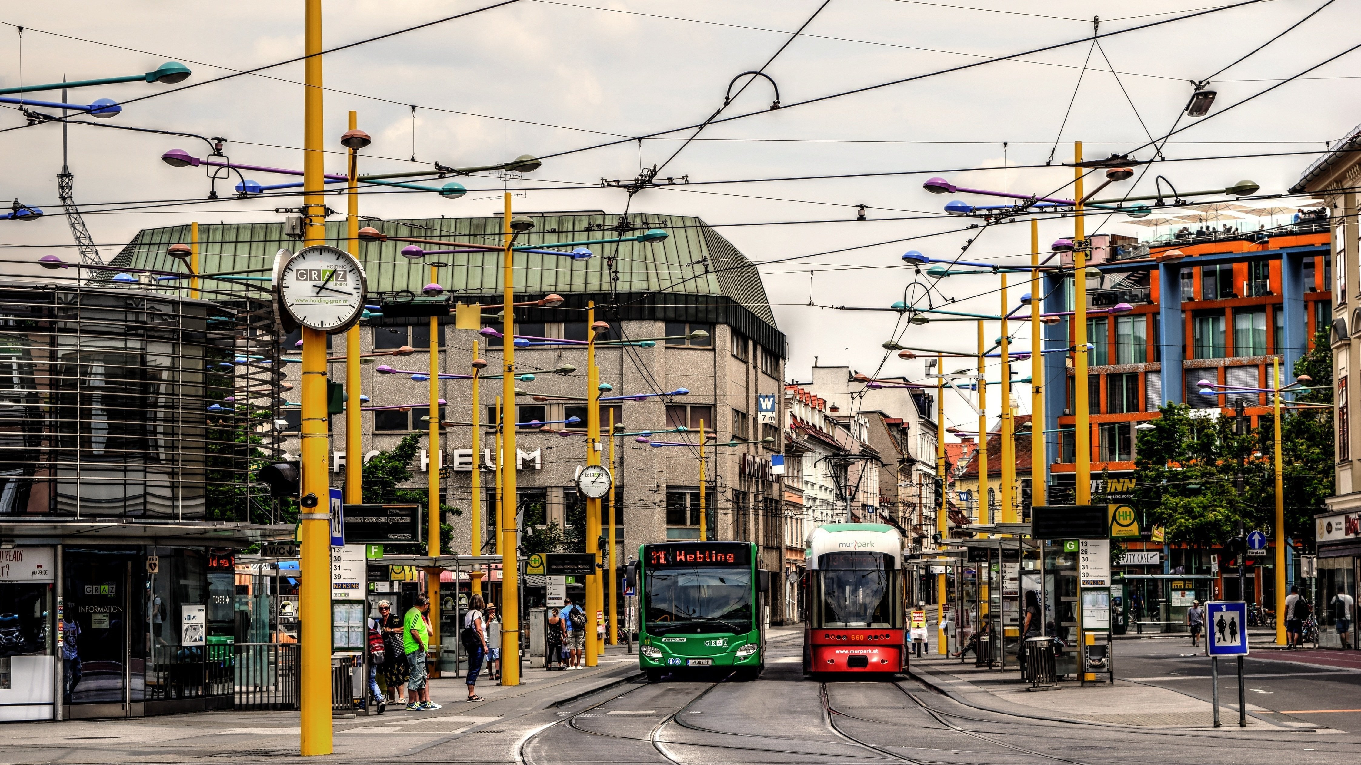 Belebte Tramhaltestelle in urbaner Umgebung Tramstation mit zwei wartenden Straßenbahnen und Menschen an der Haltestelle in einer Stadtlandschaft