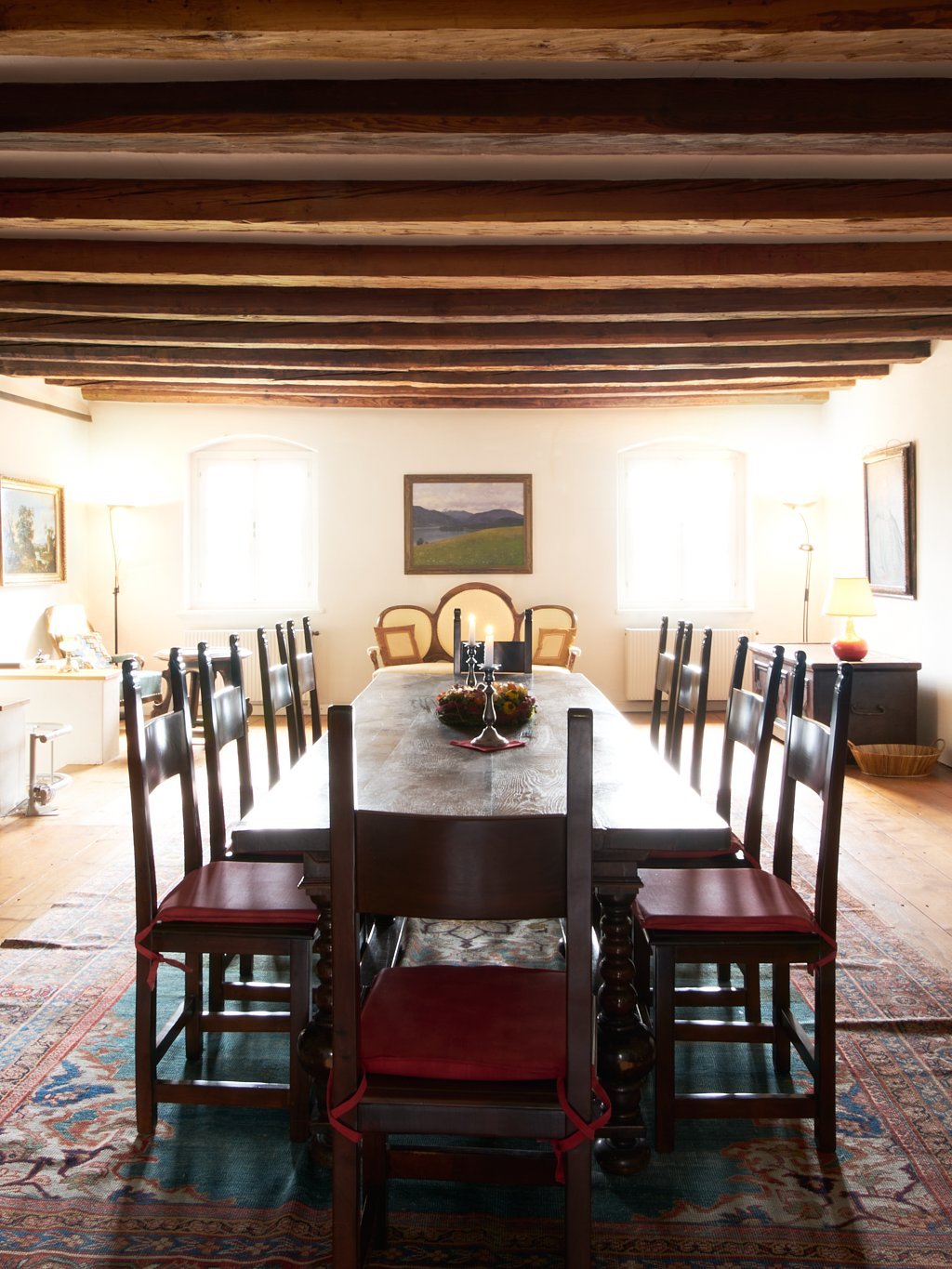 Geräumiger Speisesaal mit langem Holztisch und Stühlen, Holzdeckenbalken verleihen rustikalen Charme.