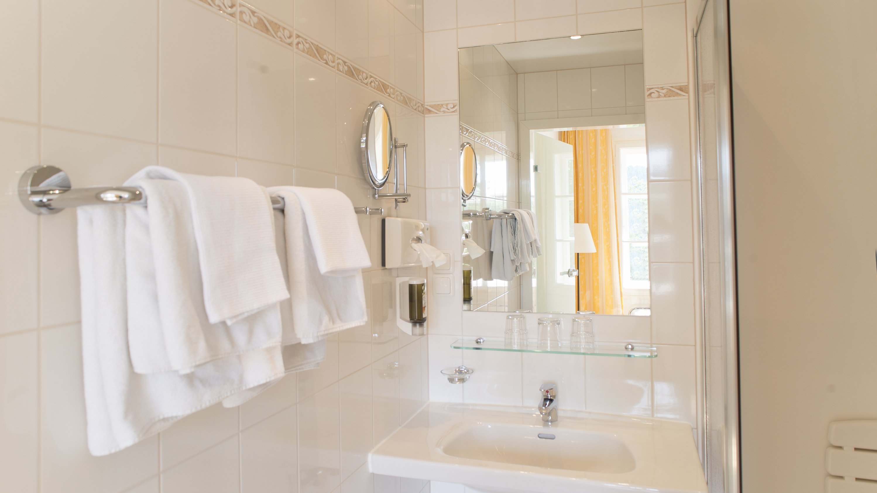 Modern Bathroom Serenity A contemporary bathroom featuring white tiles, a sleek sink, and neatly arranged towels.