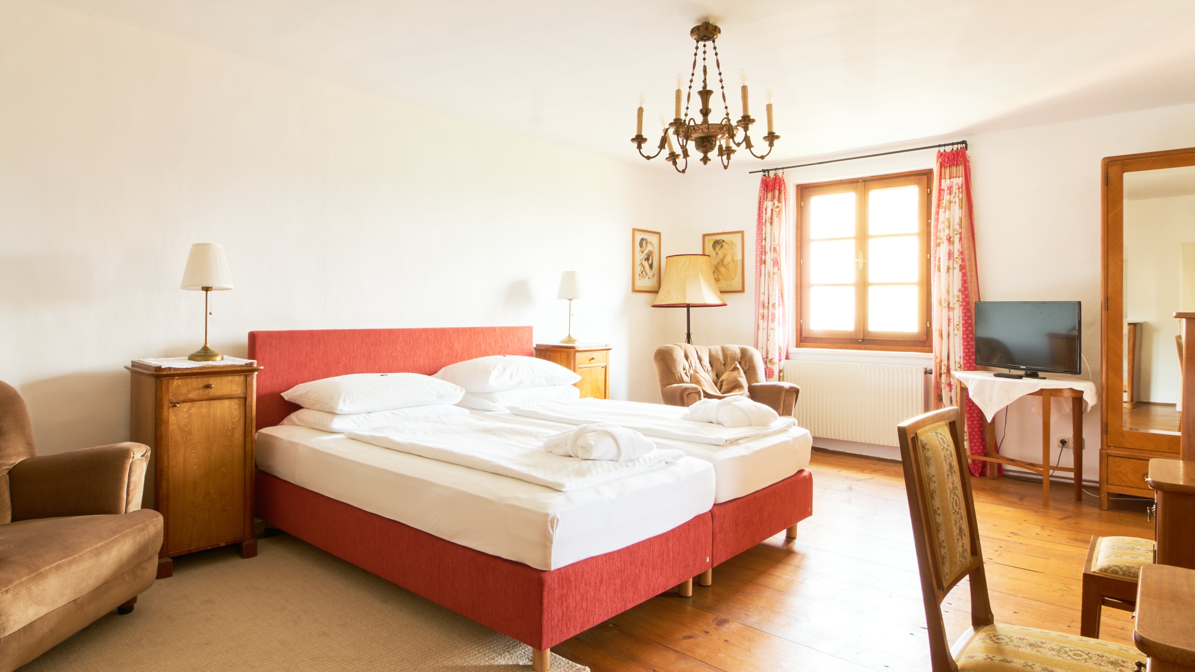 Elegantes Zimmer im Hotel Landsitz Pischlschloss Furnished hotel room with two beds and a chandelier providing soft lighting in a warm atmosphere