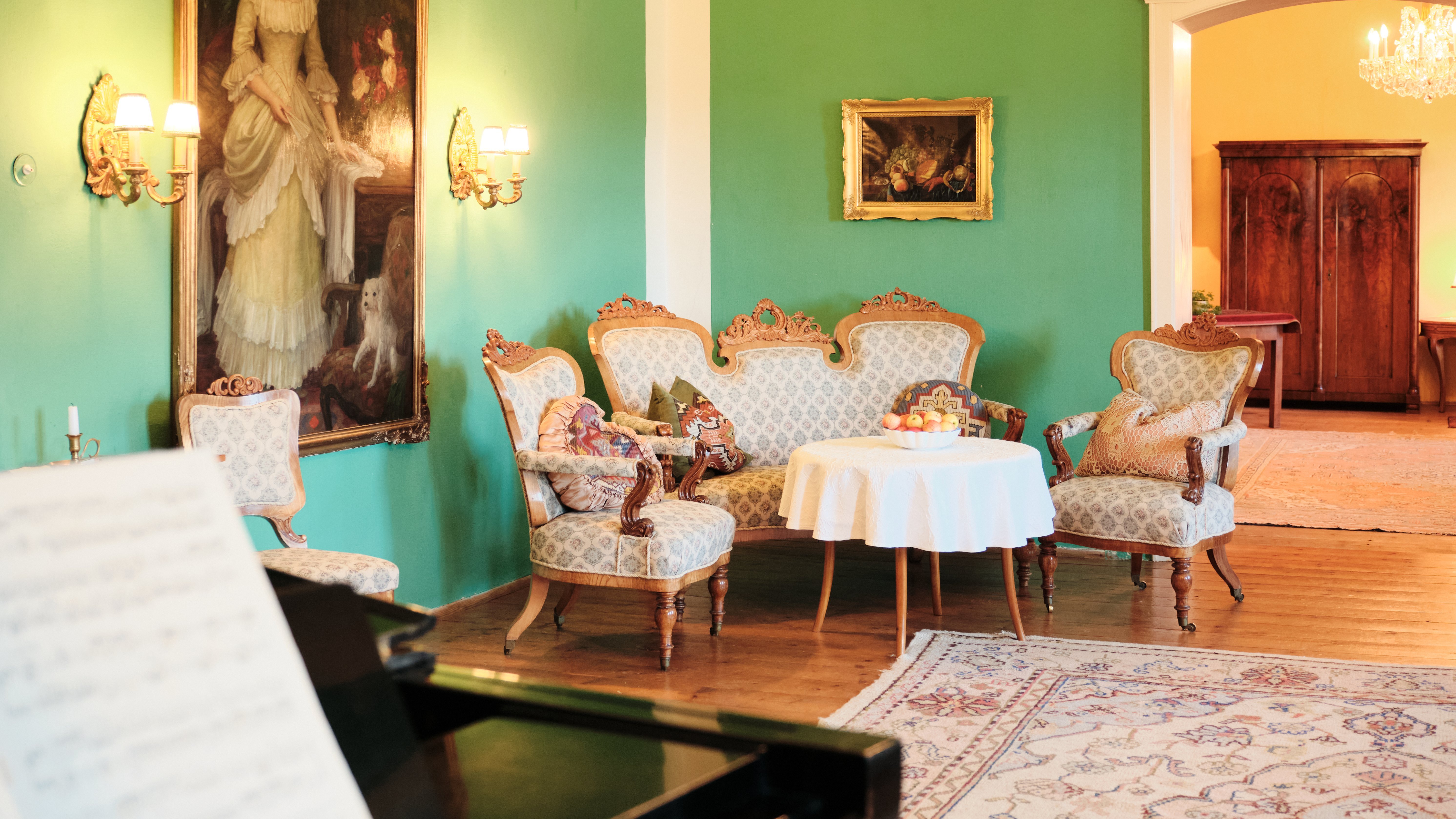 Elegantes Wohnzimmer im Vintage-Stil Vintage-Wohnzimmer mit grünen Wänden und kunstvollen Möbeln um einen kleinen Tisch.