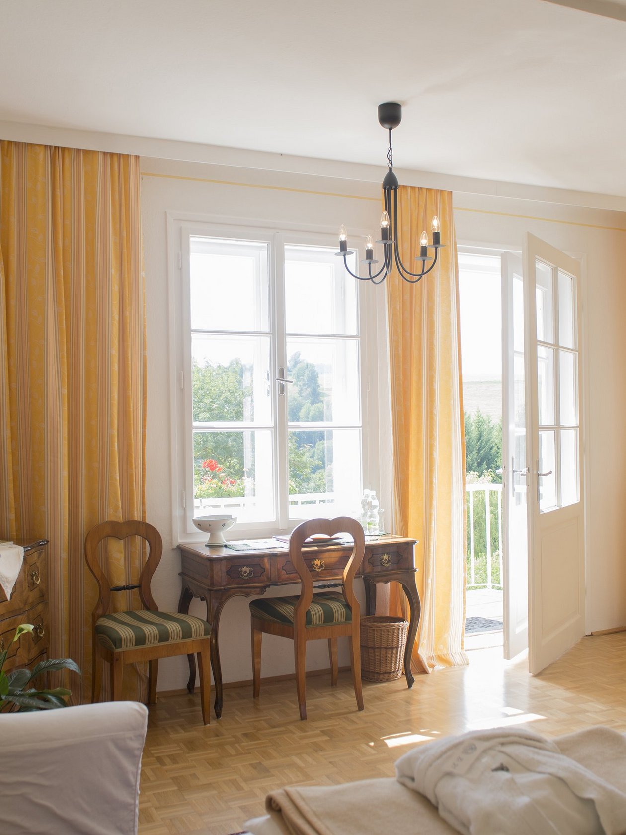 Helles Wohnzimmer mit stilvoller Einrichtung Ein helles Wohnzimmer mit großen Fenstern und einer gemütlichen Einrichtung, einschließlich Tisch und Stühlen.