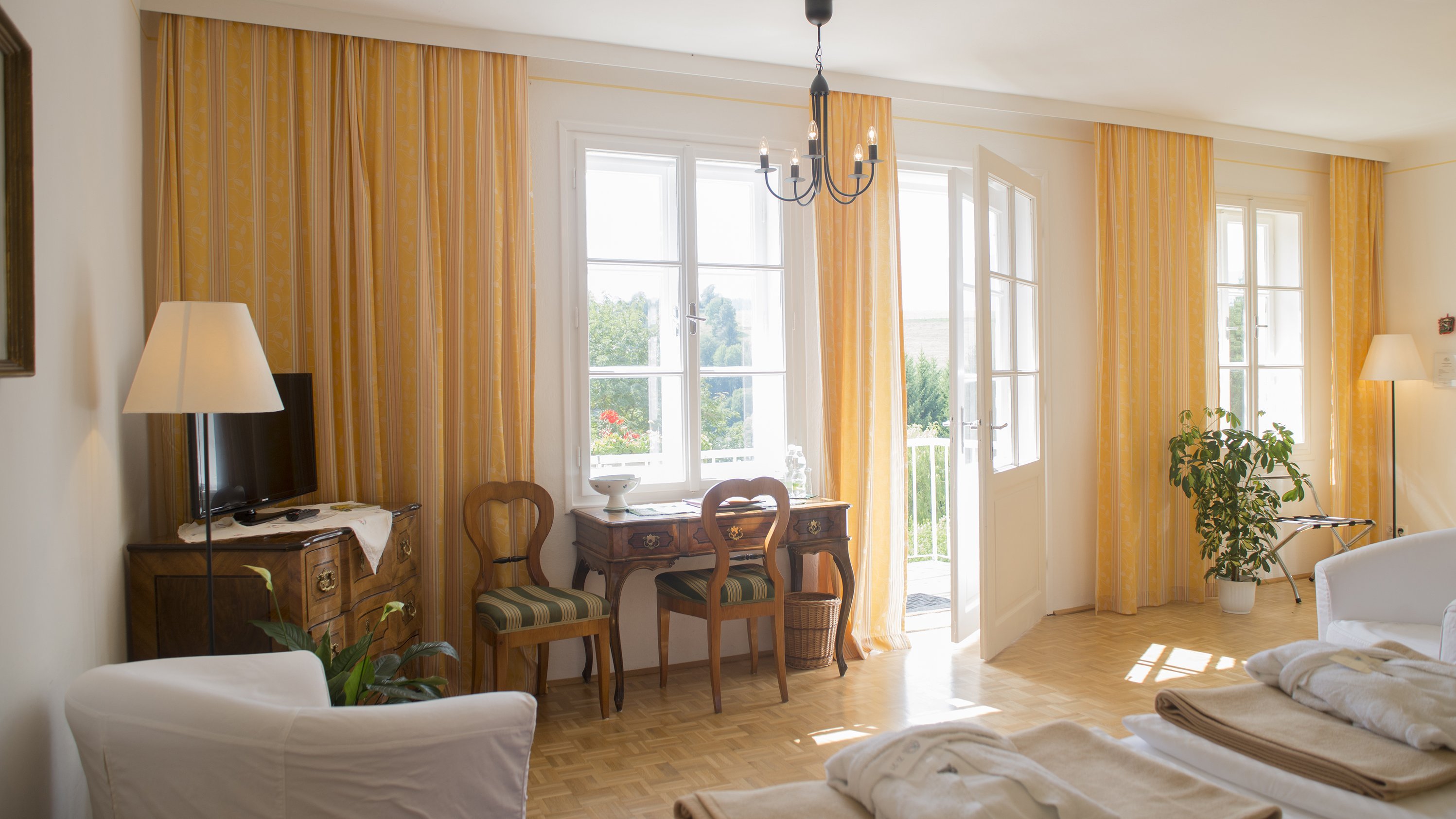 Helles Wohnzimmer mit stilvoller Einrichtung Ein helles Wohnzimmer mit großen Fenstern und einer gemütlichen Einrichtung, einschließlich Tisch und Stühlen.