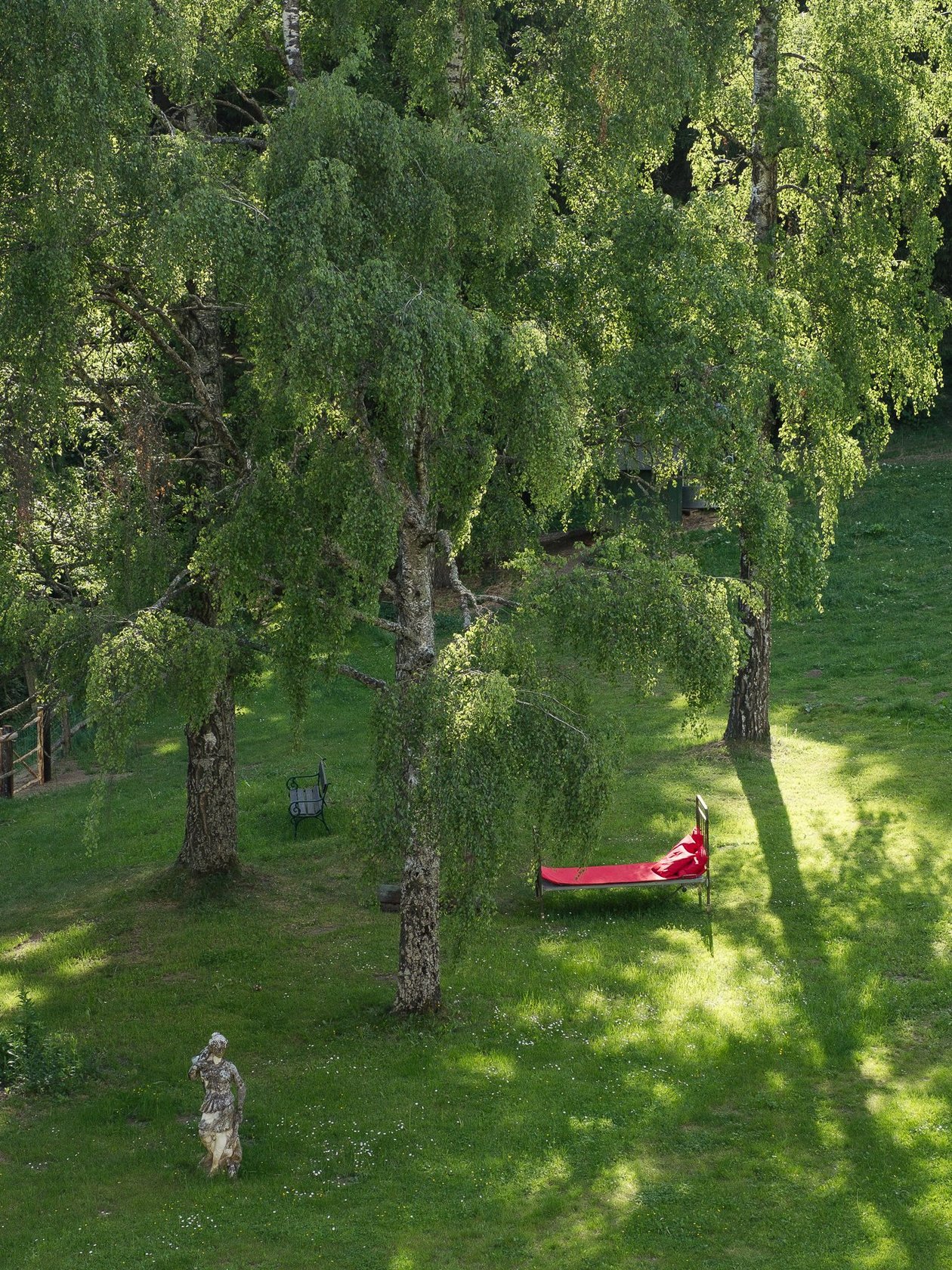 Naturidylle im Freien Rote Liege unter Bäumen auf grünem Gras in einer ruhigen Landschaft mit Waldatmosphäre.