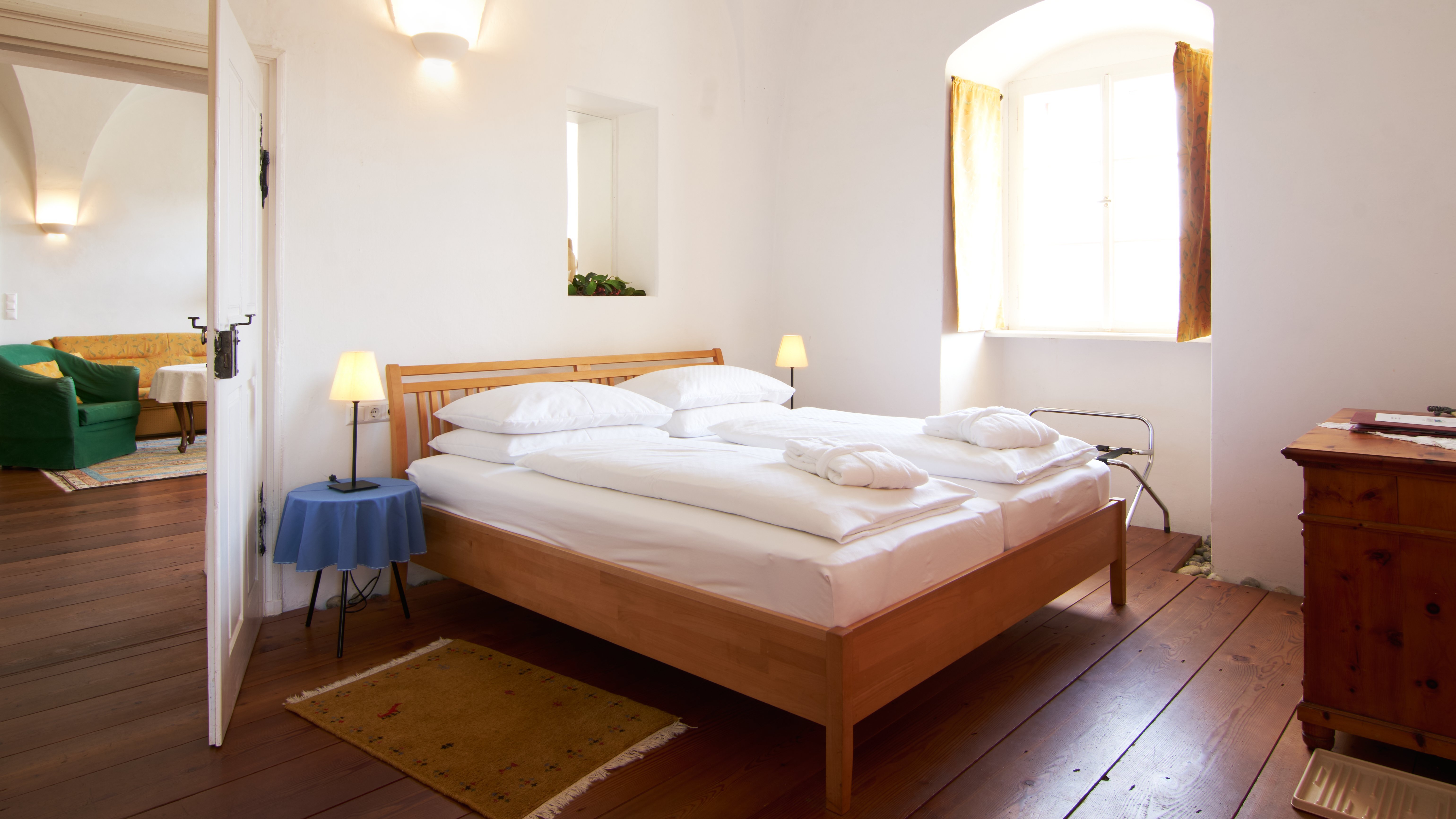 Bright airy bedroom with natural light A spacious bedroom featuring a wooden bed, white bedding, and large windows for abundant natural light.