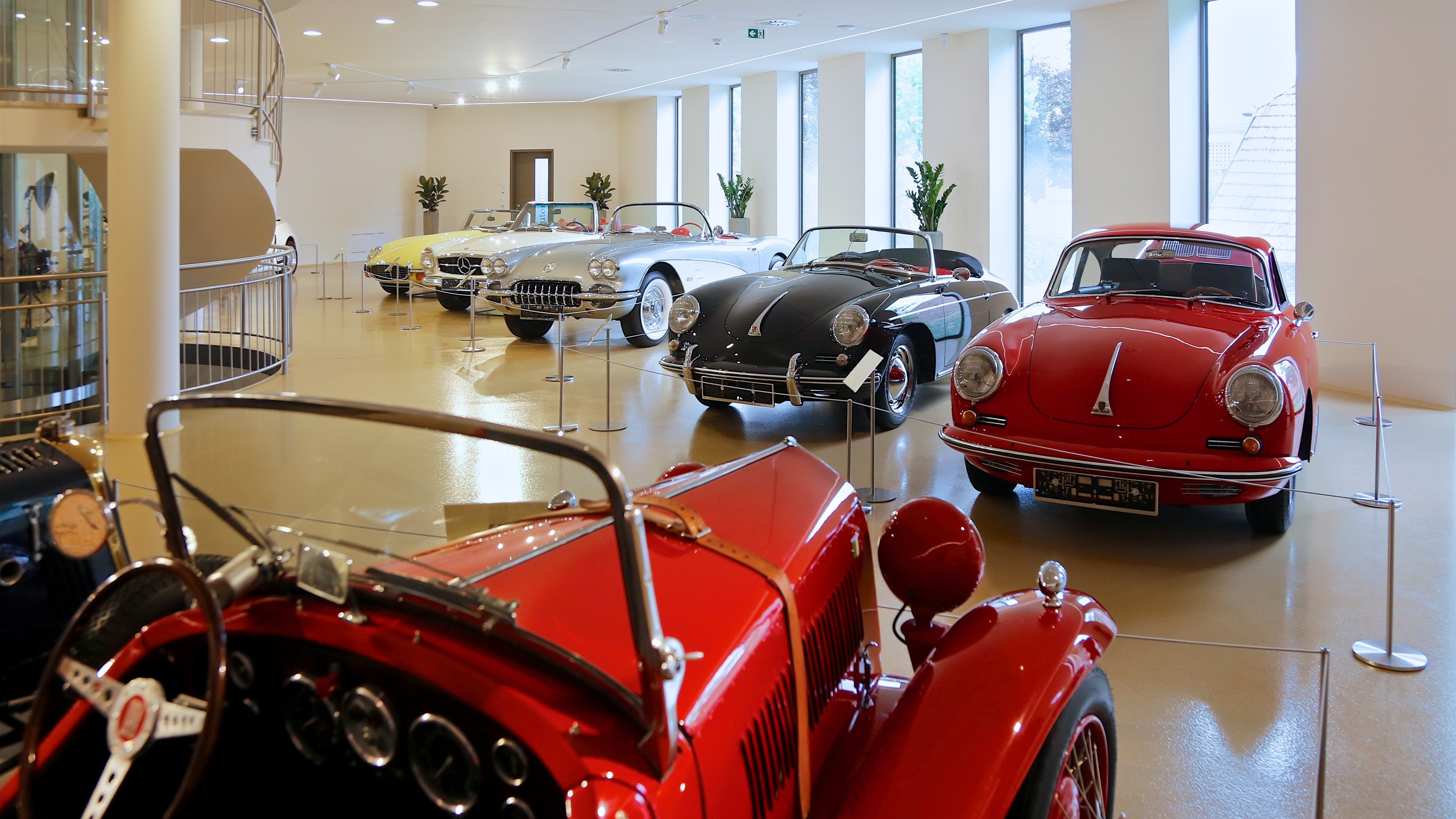 Eine Sammlung von klassischen und luxuriösen Autos in einem modernen Showroom mit großen Fenstern