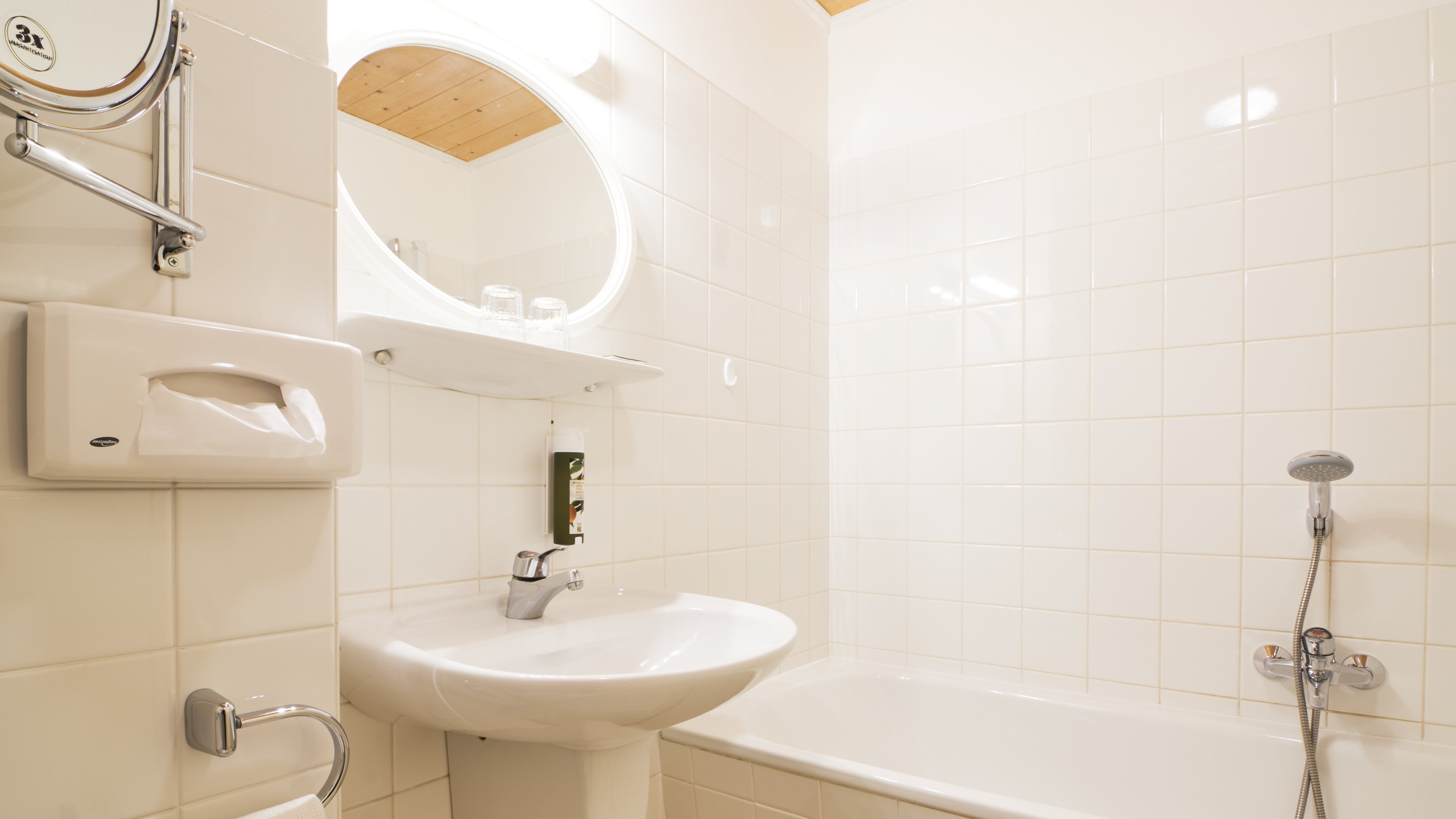 Moderne Badgestaltung für erholsame Momente Helles Badezimmer mit Waschbecken, Badewanne und runder Wandspiegelanordnung auf Fliesen