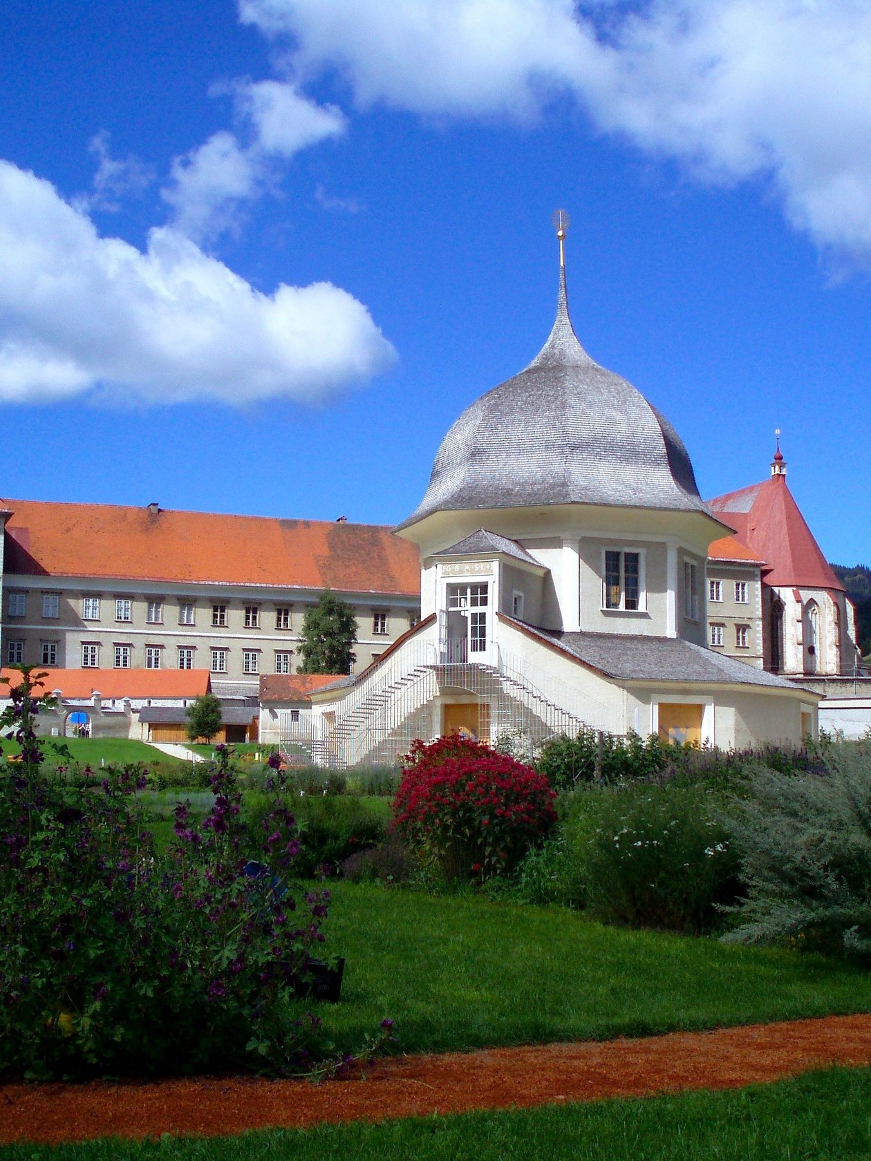 Historisches Gebäude im Garten Ein historisches Gebäude mit einer markanten Kuppel und gepflegten Gärten umgeben von sanften Hügeln.
