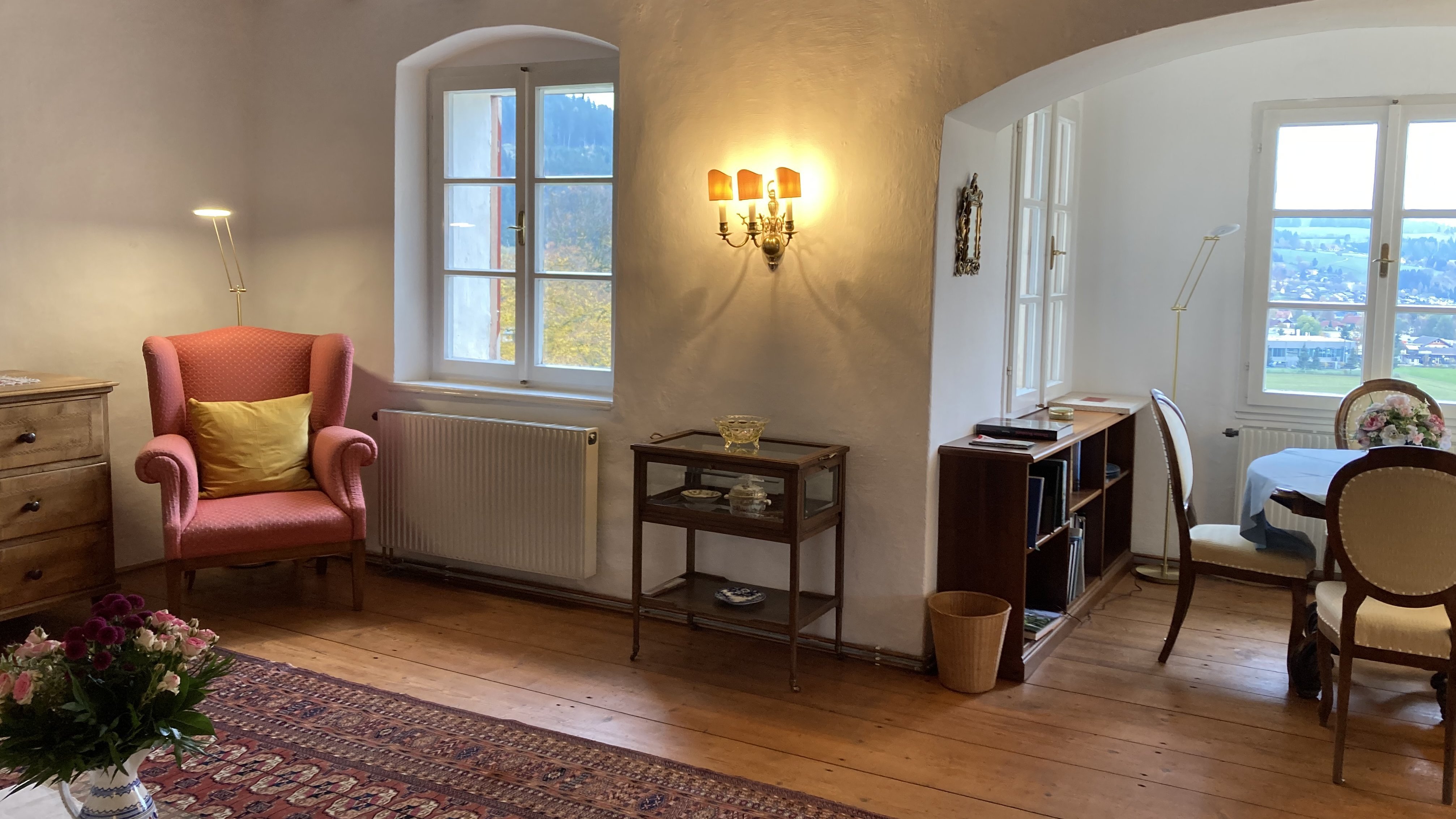 Behagliches Wohnzimmer mit pinkem Sessel, Holzbalken und großen Fenstern für Tageslicht