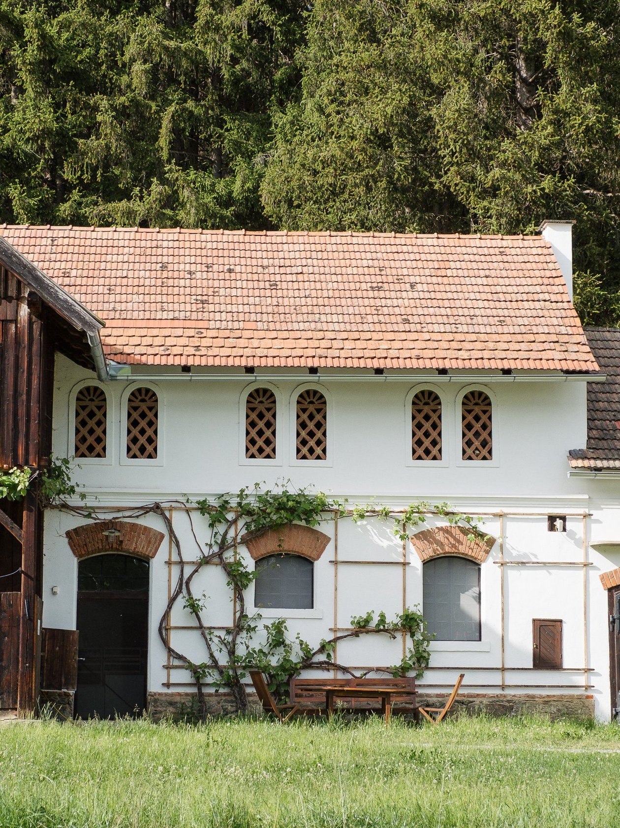 Nebengebäude des Pichlschlosses Eine rustikale Hütte mit einem ziegelgedeckten Dach, umgeben von Grünflächen und Bäumen.