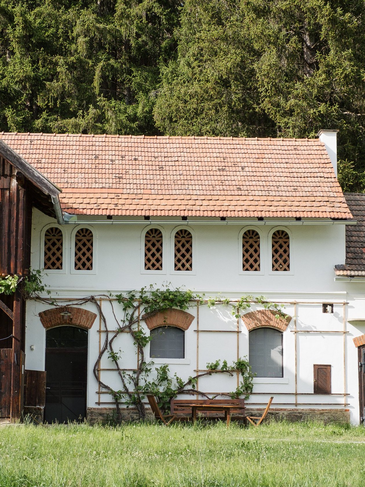 Outbuilding of Pichlschloss Rustic country house with white exterior and wooden accents surrounded by greenery