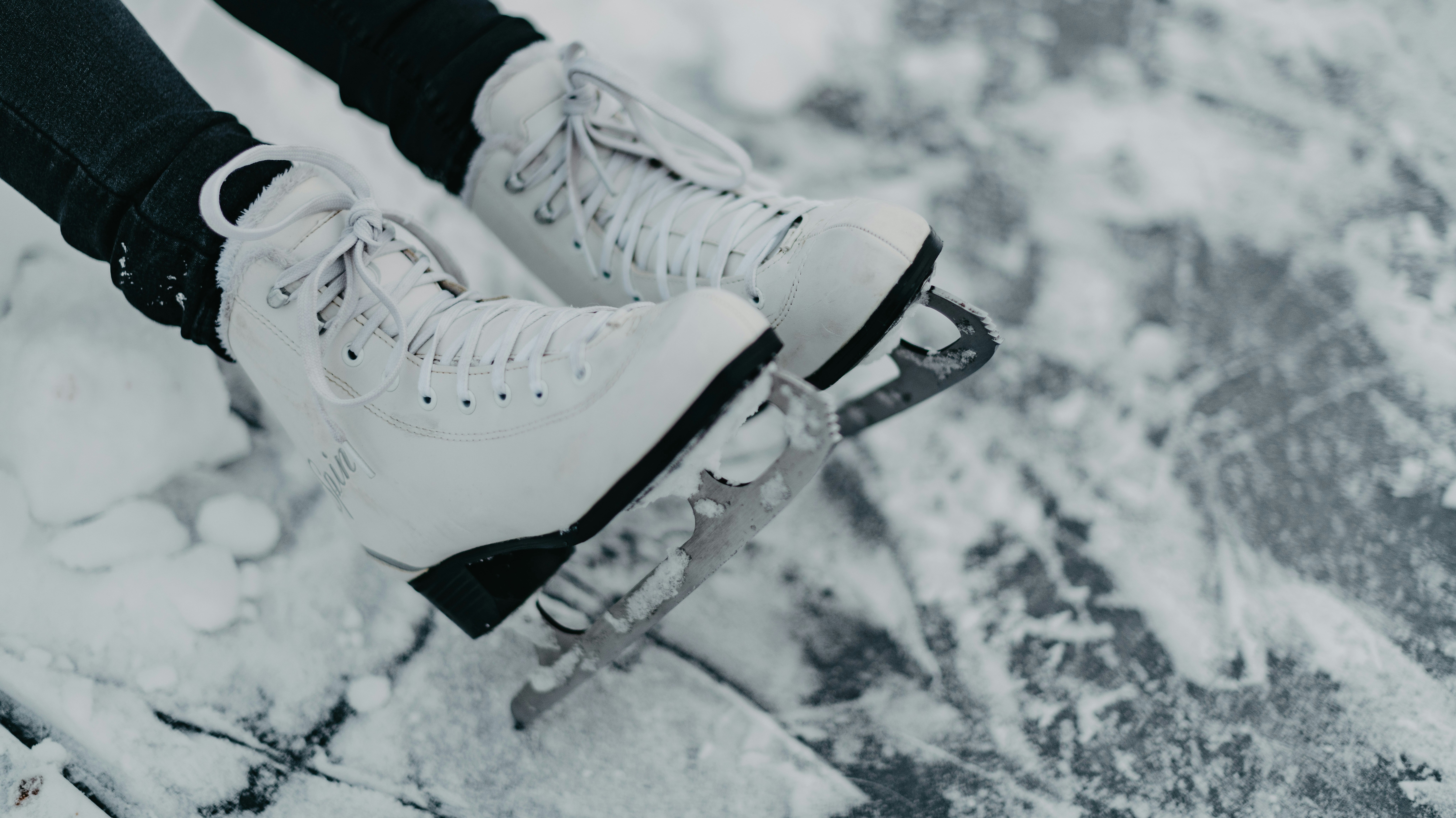 Winterliche Eislaufabenteuer Die Füße einer Person in weißen Schlittschuhen auf einer verschneiten Fläche beim Eislaufen