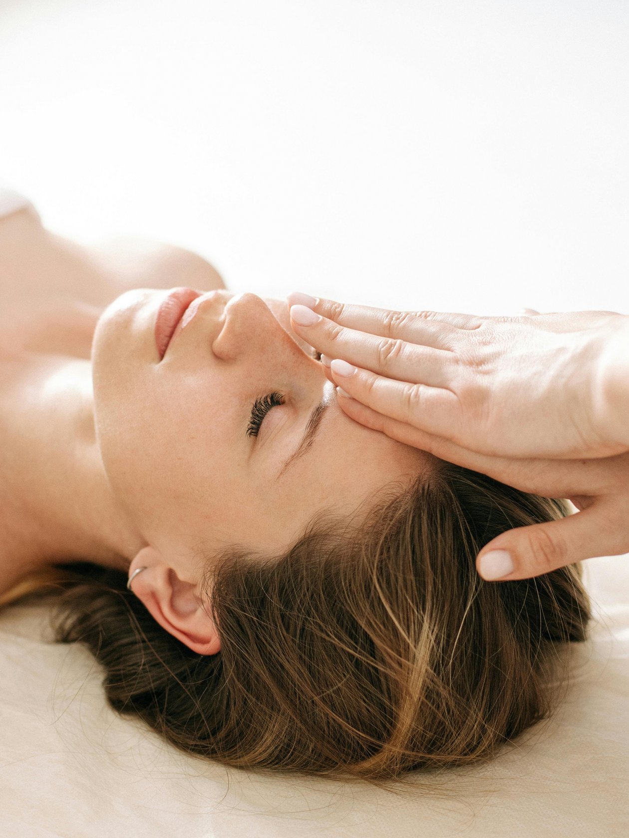 Eine Frau erhält eine Gesichtsmassage von einer Therapeutin mit sanften Händen, die Entspannung vermittelt.