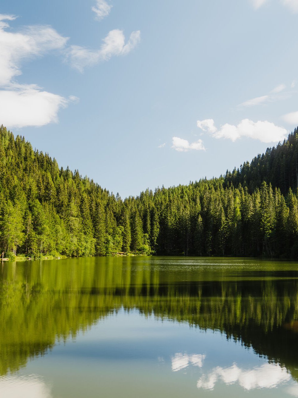 Ruhe am Auerlingsee Spiegelbild des klaren Wassers im Auerlingsee, umgeben von dichten Wäldern und Bergen.