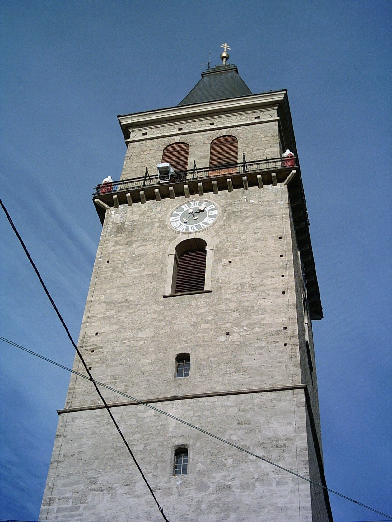 Historischer Stadtturm in Murau Hoher Steinturm mit Ziffernblatt und Spitzdach unter blauem Himmel, historisches Architekturmerkmal.