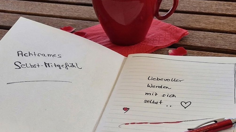 Notizen zur Selbstmitgefühls-Praxis Ein offenes Notizbuch mit handschriftlichen Notizen über Selbstmitgefühl und einer Tasse Kaffee.