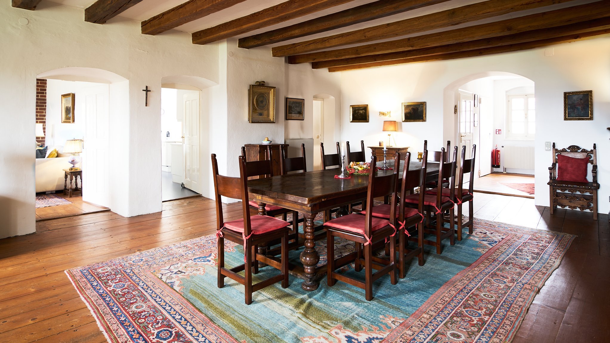 Rustikales Esszimmer mit traditionellem Flair Geräumiges Esszimmer mit großem Holztisch und Stühlen, dekorativen Teppichen und sichtbaren Holzträgern