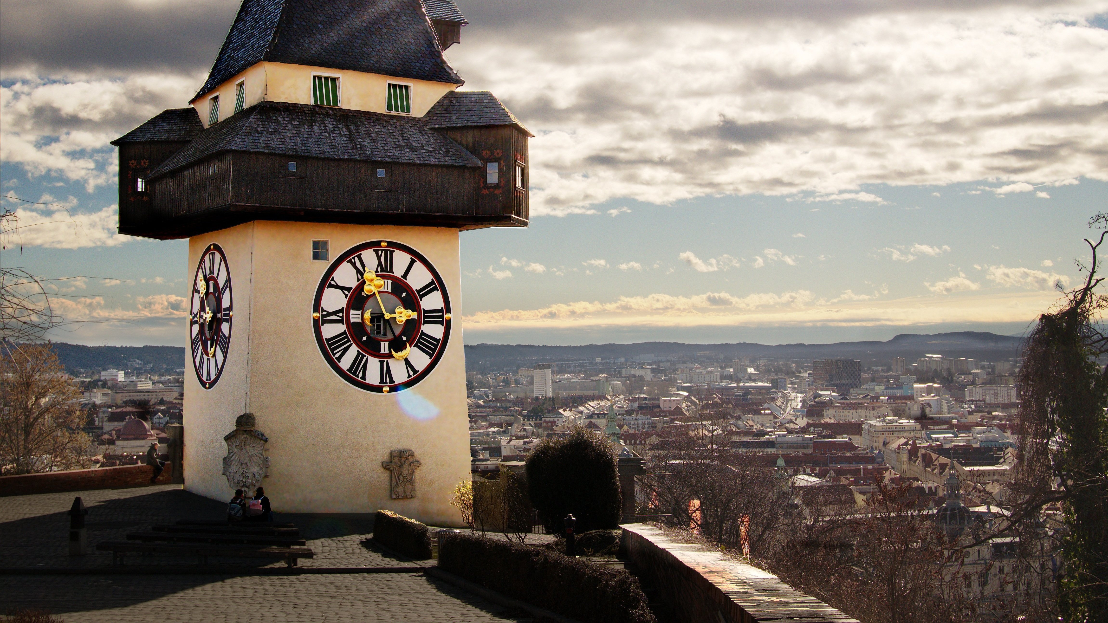 Uhrturm in Graz Architektonischer Uhrturm auf einem Hügel über der Stadt Graz mit Wolken im Hintergrund