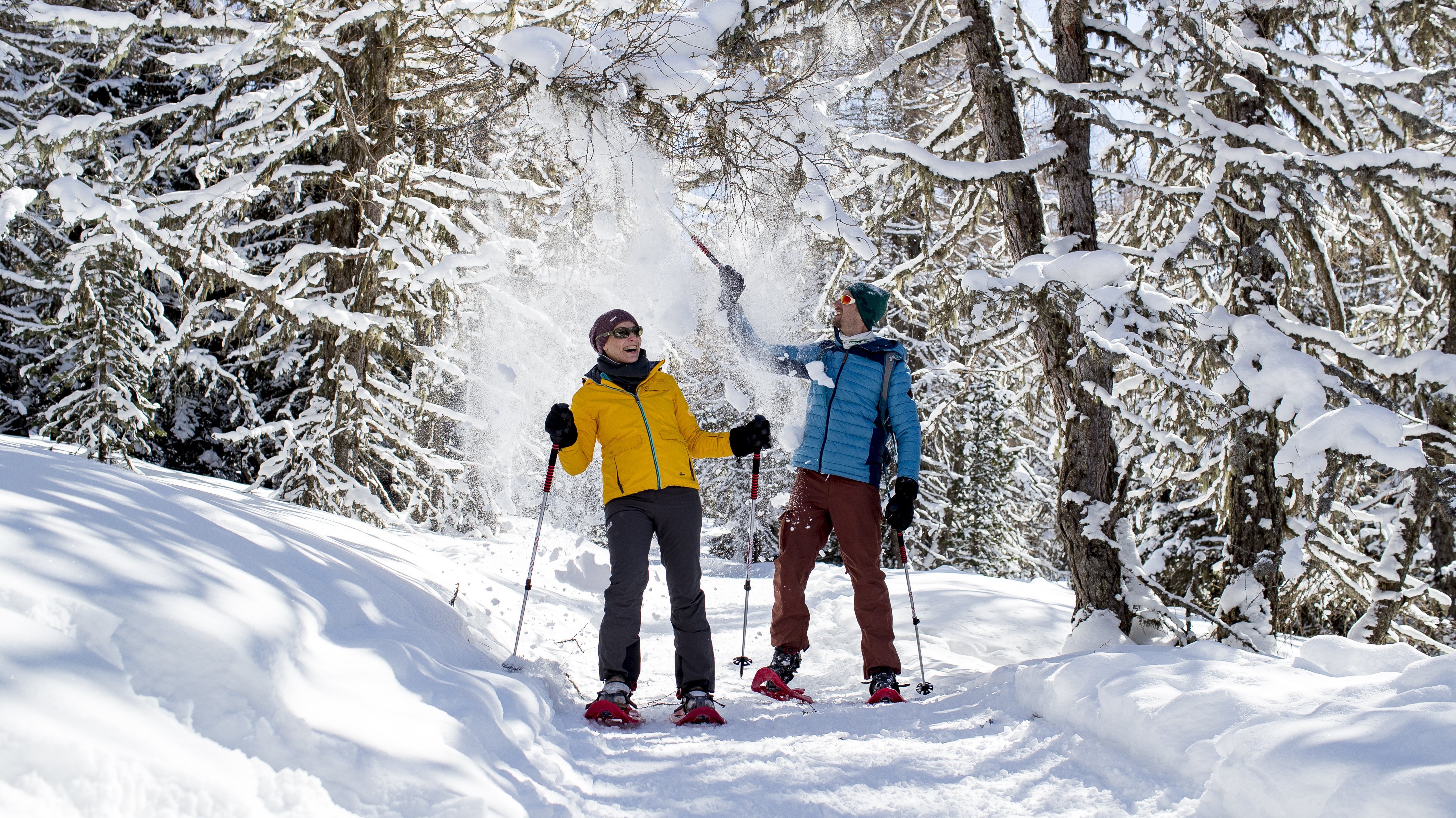 Schneeschuhabenteuer am Zirbitzkogel Zwei Personen beim Schneeschuhwandern in einem verschneiten Wald, Schnee wird in die Luft geworfen