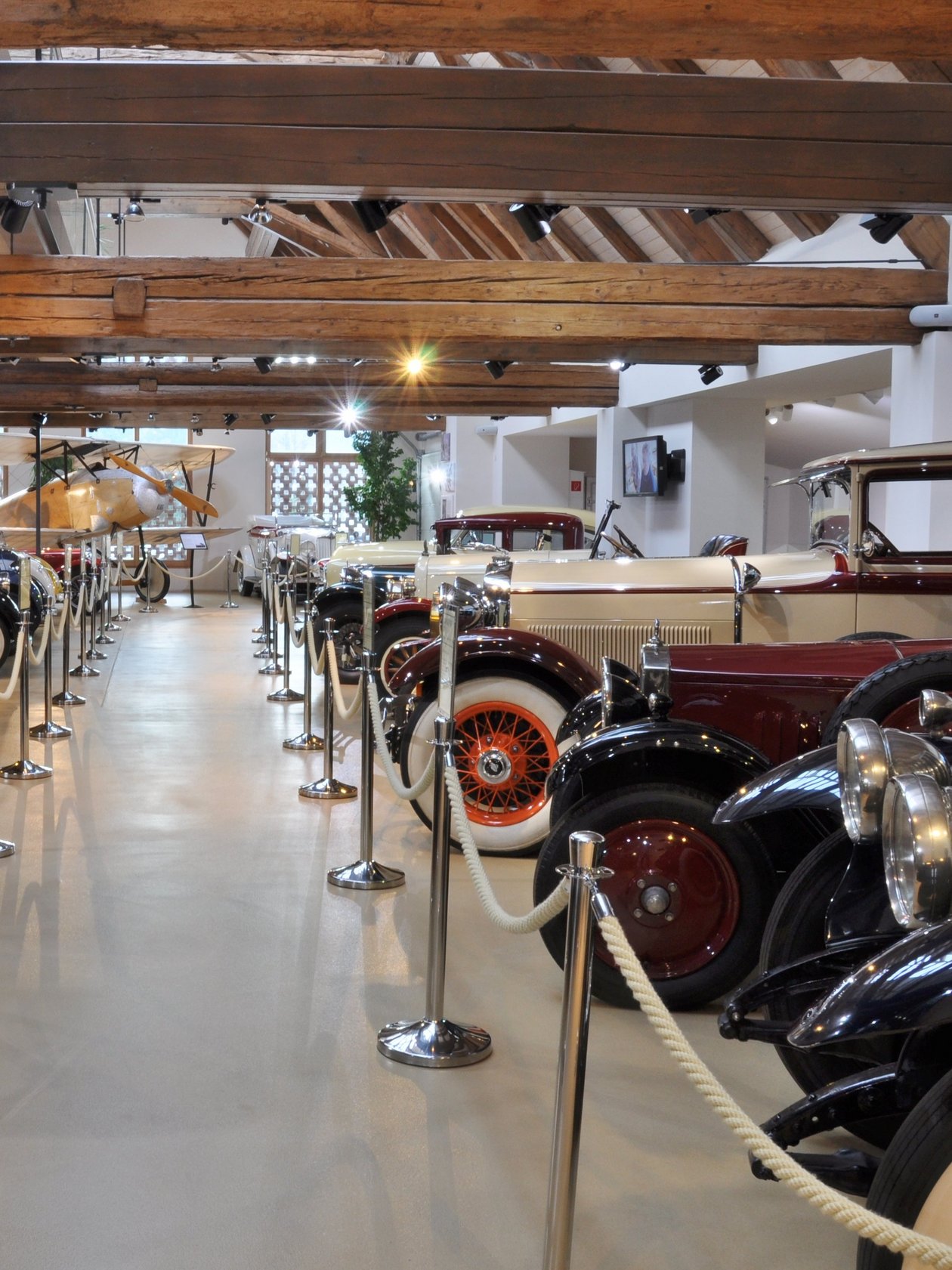 Historische Automobile im Museum Ein Raum mit Oldtimern unter Holzbalken in einem Automobilmuseum. Vintage Fahrzeuge sind aufgereiht.